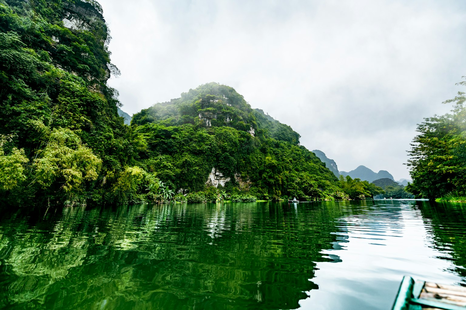 Danau hijau yang tenang dengan refleksi gunung di sekitarnya