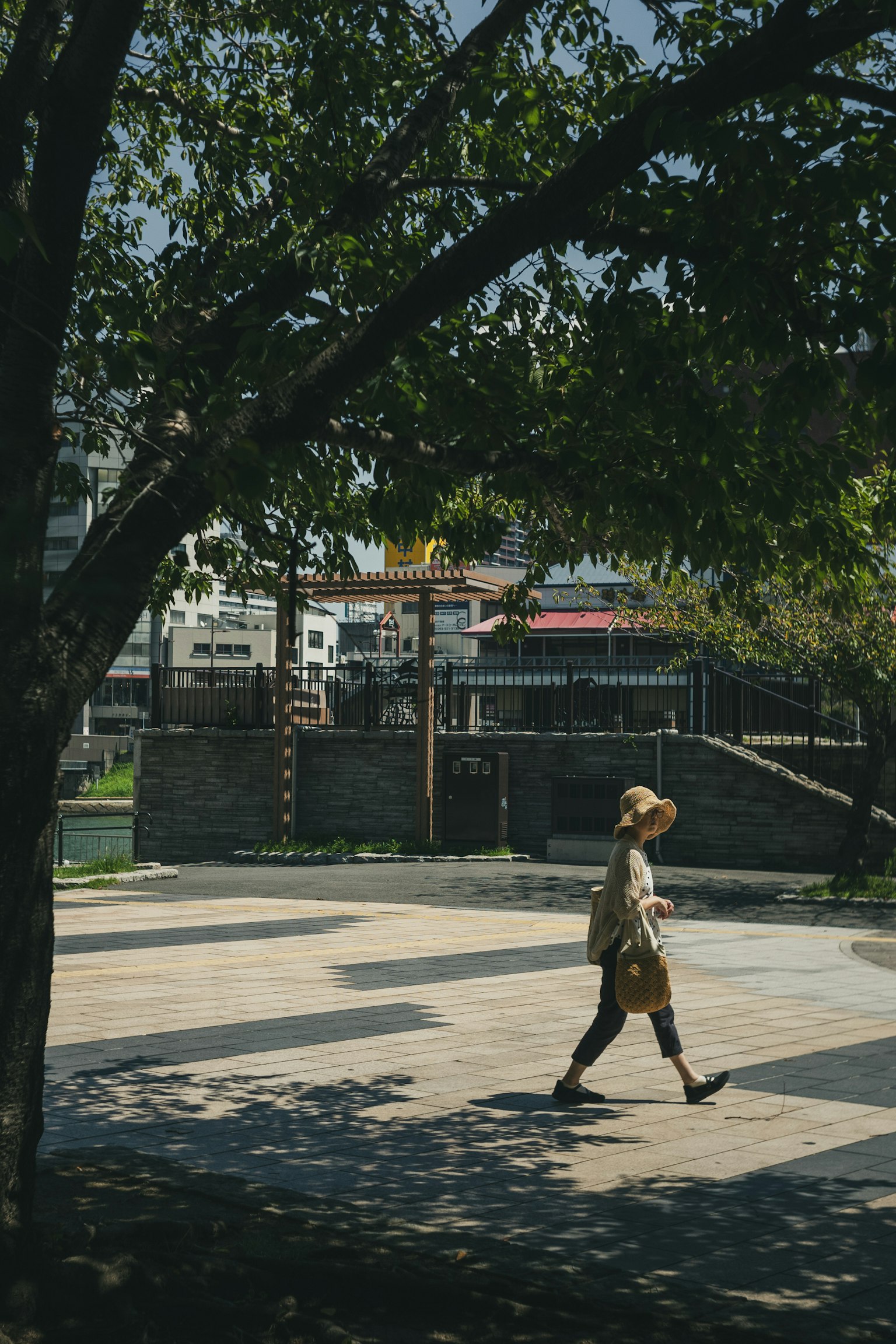 ภาพด้านข้างของผู้หญิงที่เดินในสวนที่มีต้นไม้เขียวขจีและแสงแดดสดใส