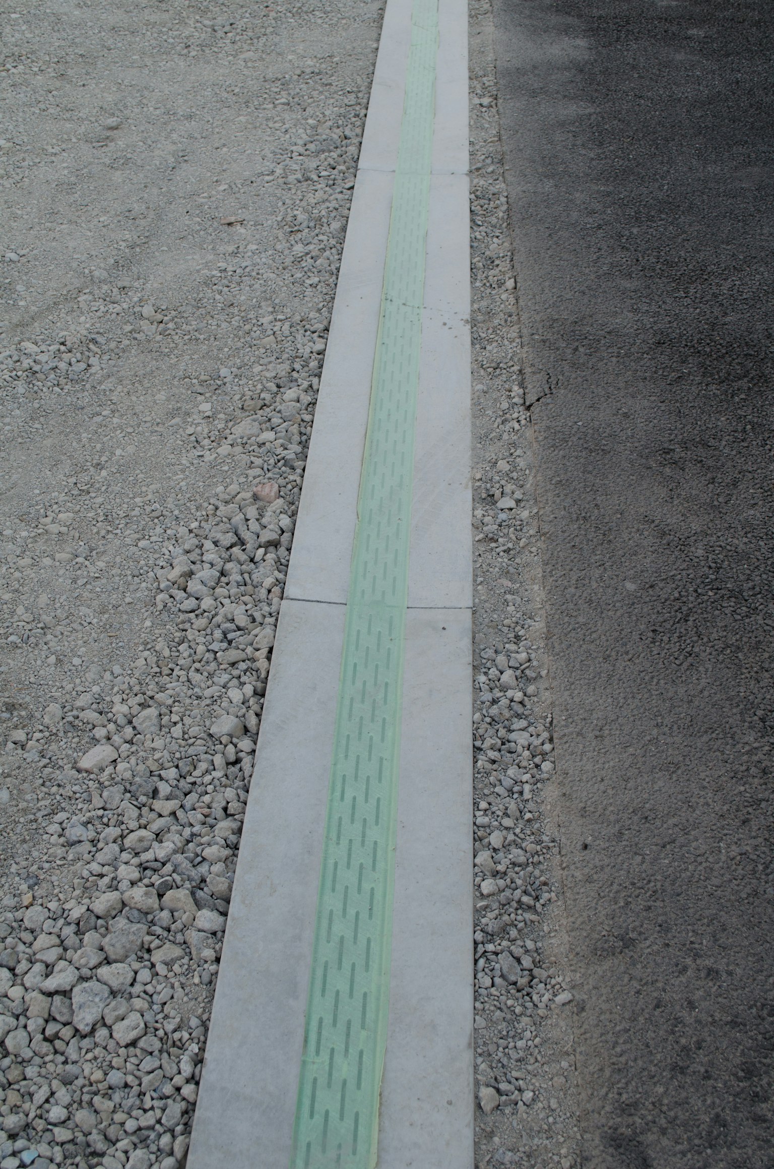 Linea verde lungo un sentiero pavimentato con superficie in ghiaia