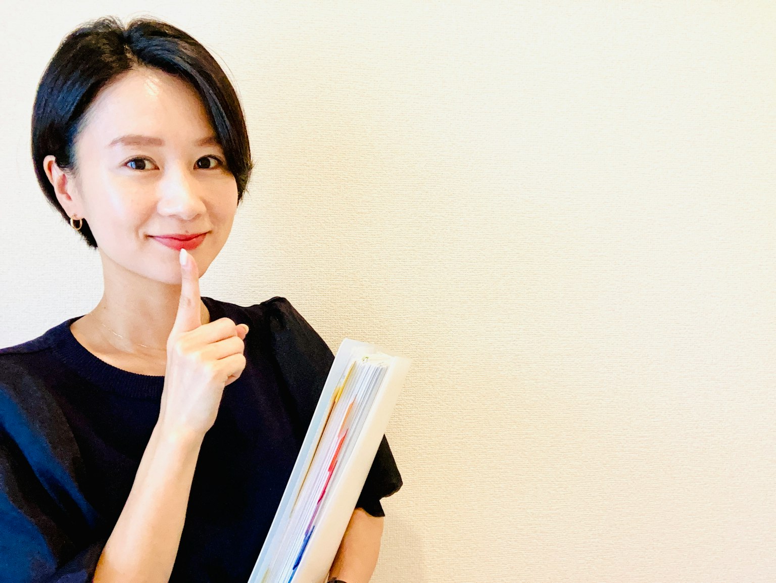 Una donna sorridente con il dito sulle labbra che tiene un libro