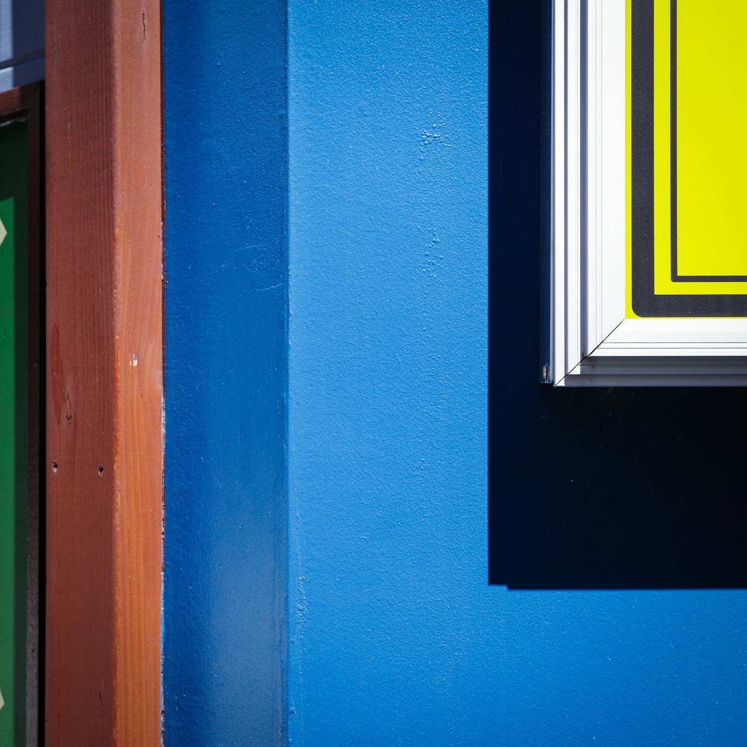 Gambar menunjukkan dinding biru dengan papan kuning yang terlihat sebagian