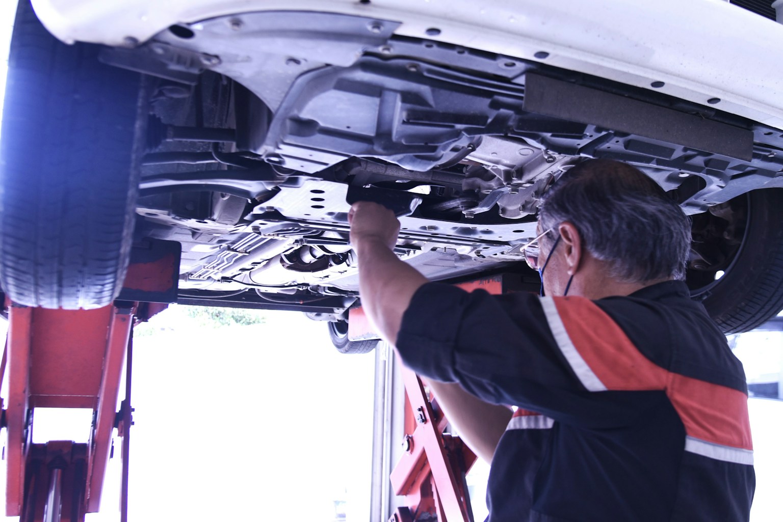 車の下で作業するメカニックの男性