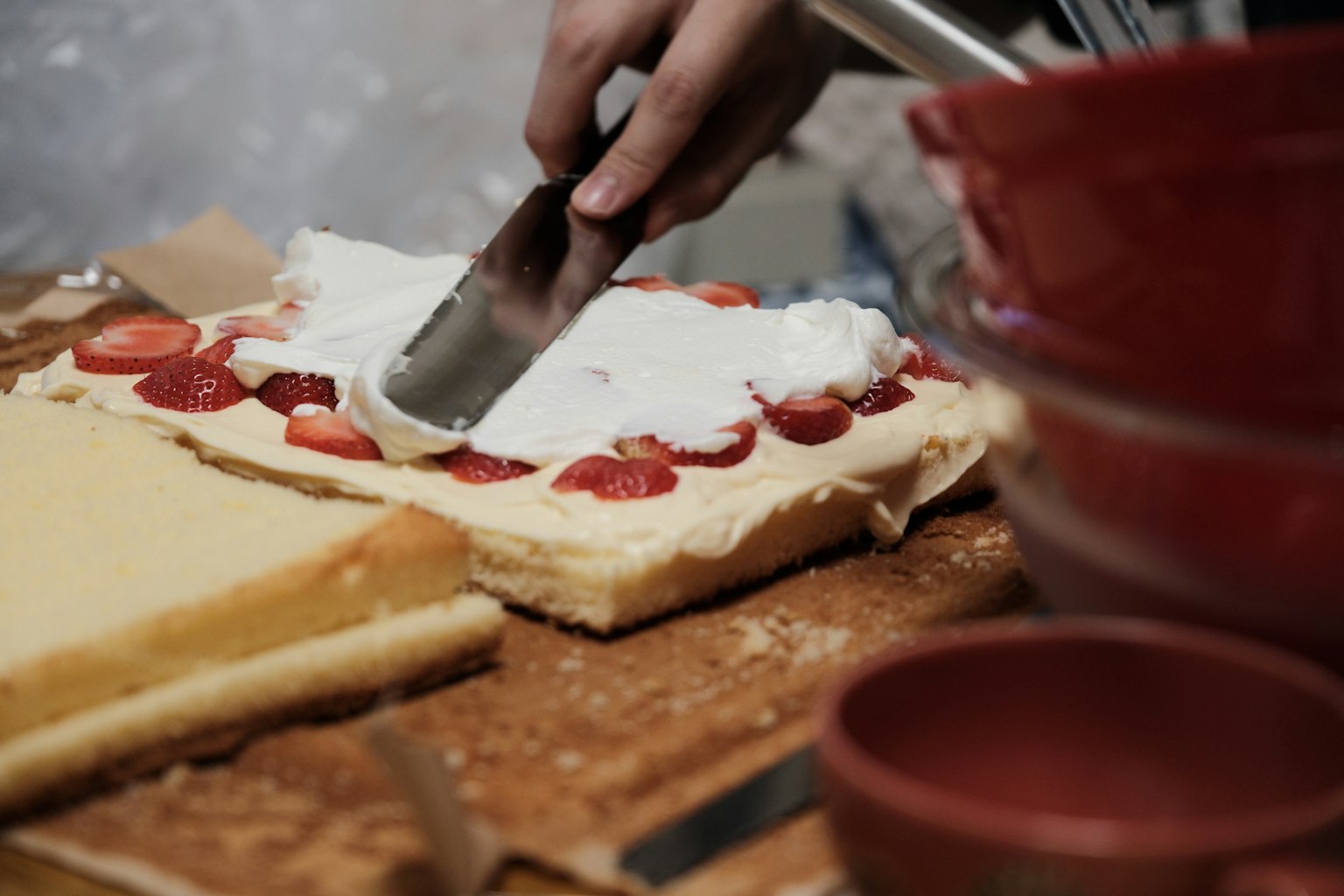 クリームとイチゴを載せたケーキを切っている手