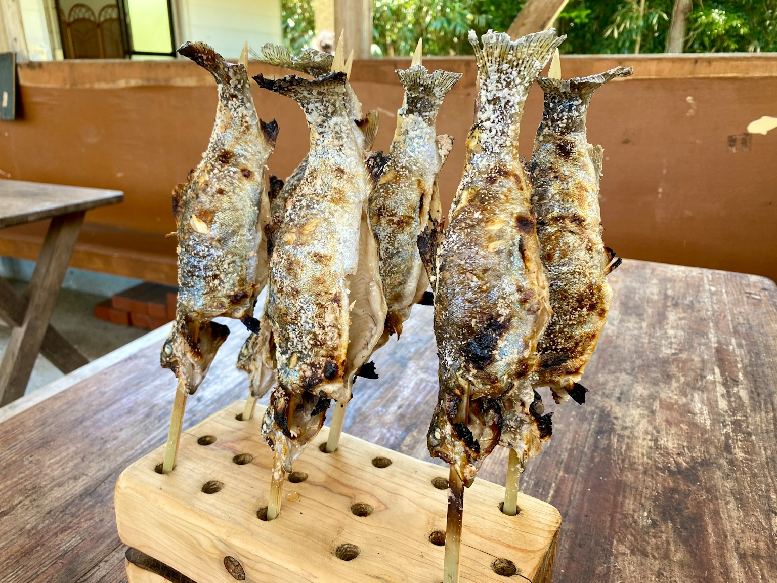 Pescado a la parrilla ensartado en un soporte de madera