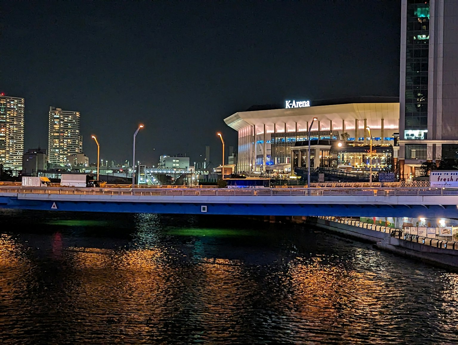 Paesaggio urbano notturno con un ponte grattacieli e riflessi sull'acqua