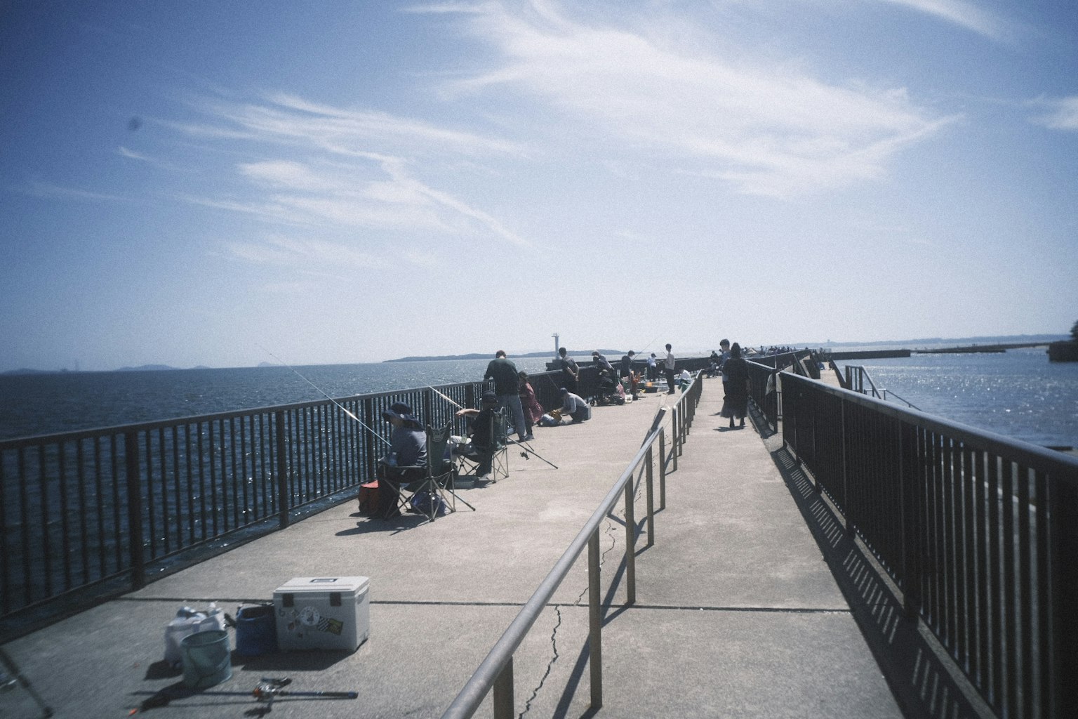Fishermen fishing from a pier with blue sky and ocean view