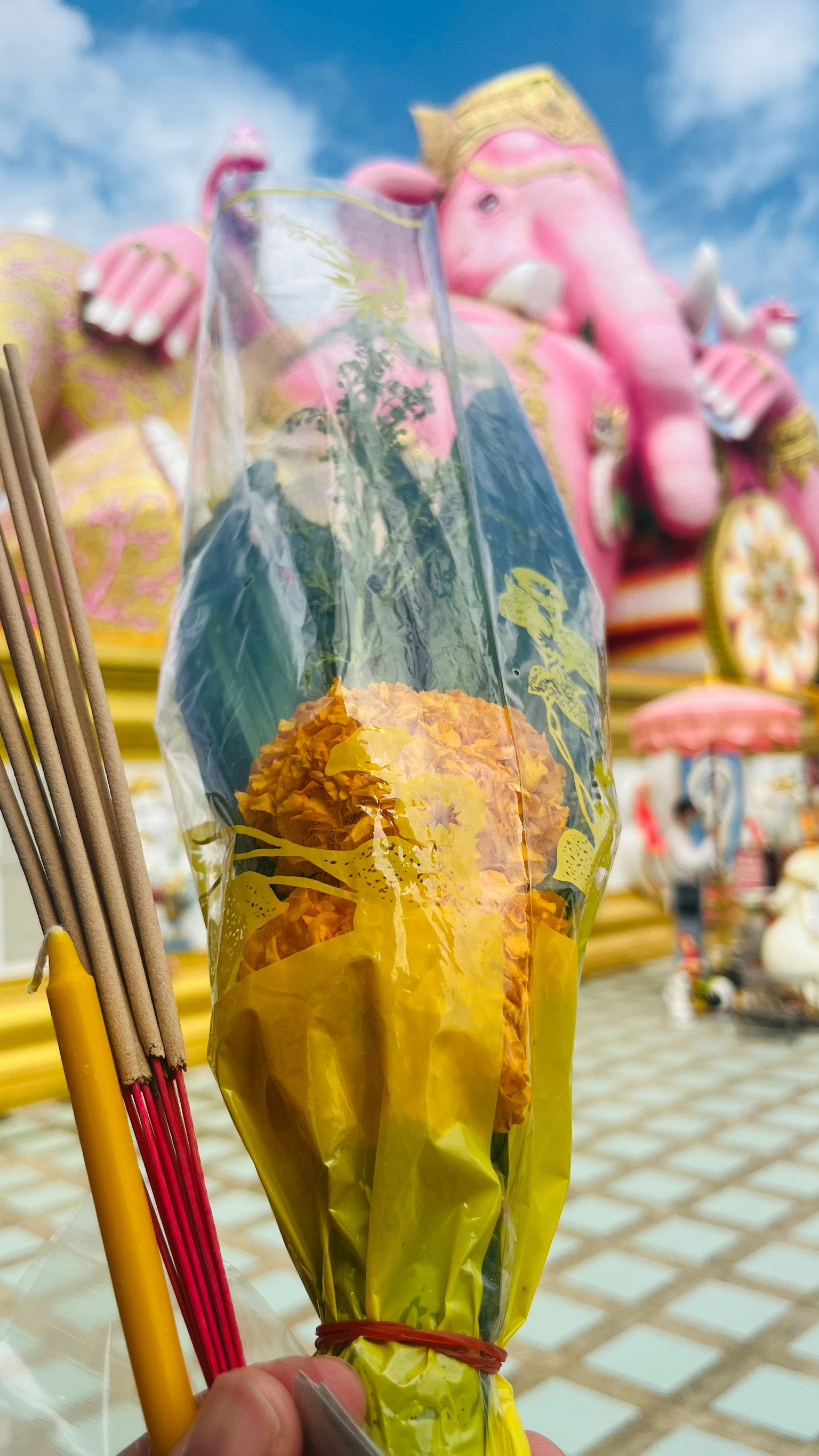 Un mazzo di fiori tenuto in mano con una grande statua di Ganesha sullo sfondo