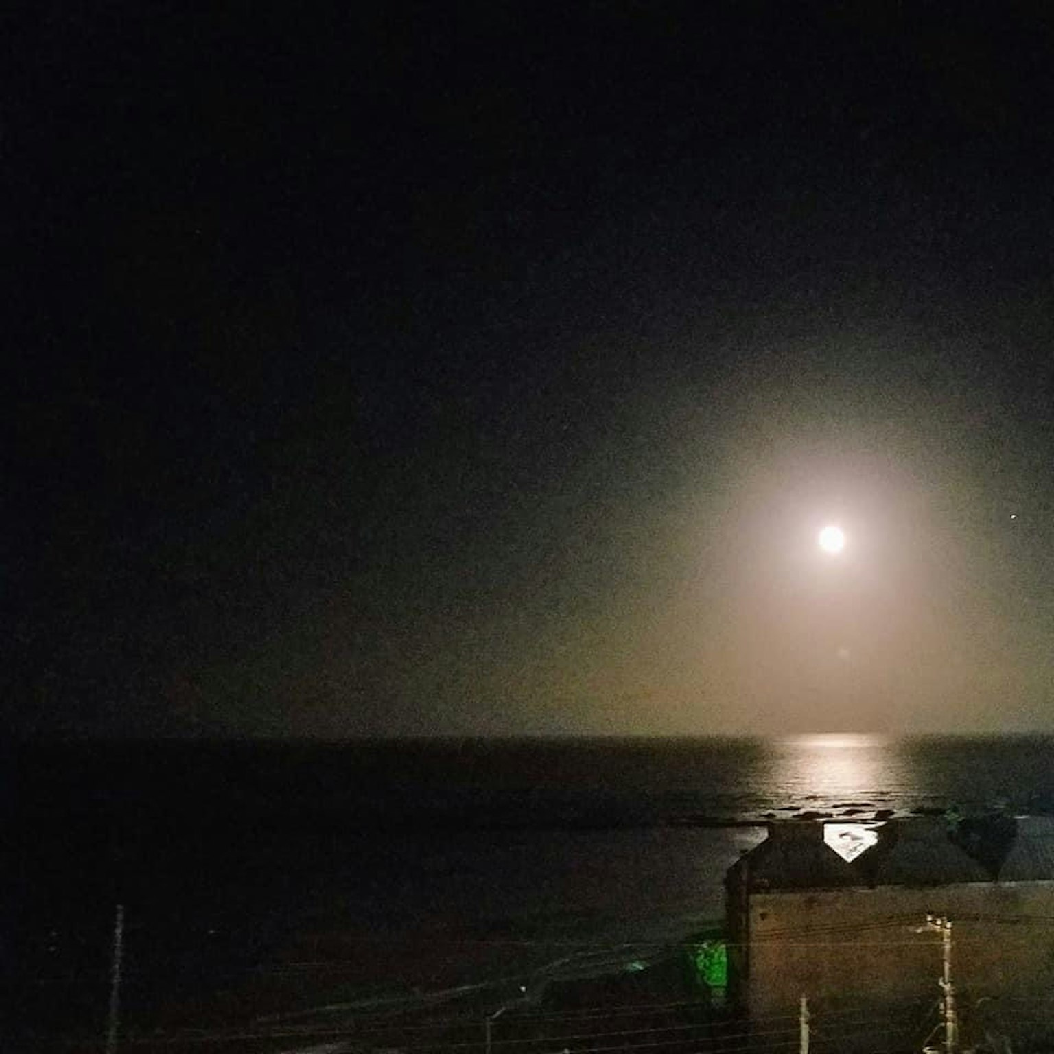 Luna brillante sopra l'oceano con un'atmosfera nebbiosa di notte