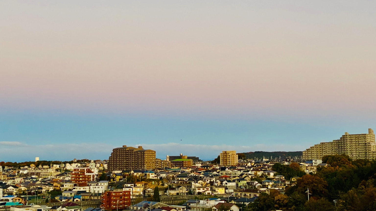 Urban landscape with pastel sky featuring high-rise buildings and residential areas