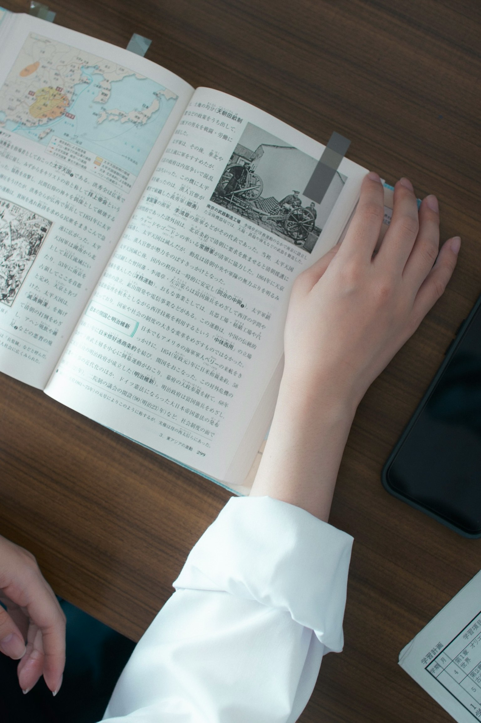 A hand resting on an open book with a photo inserted between the pages