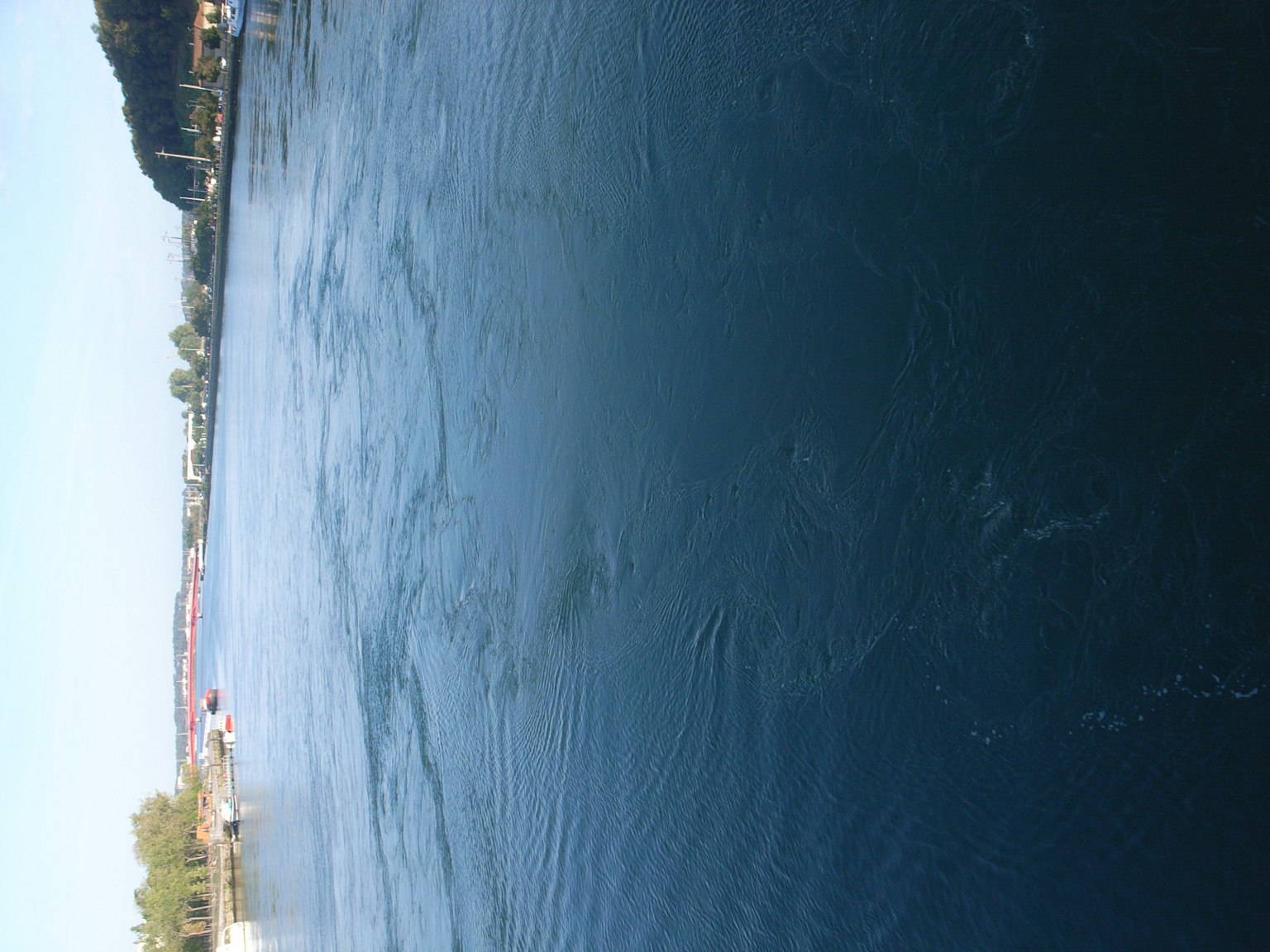 Ruhige Wasseroberfläche mit blauem Himmel über einer Seelandschaft
