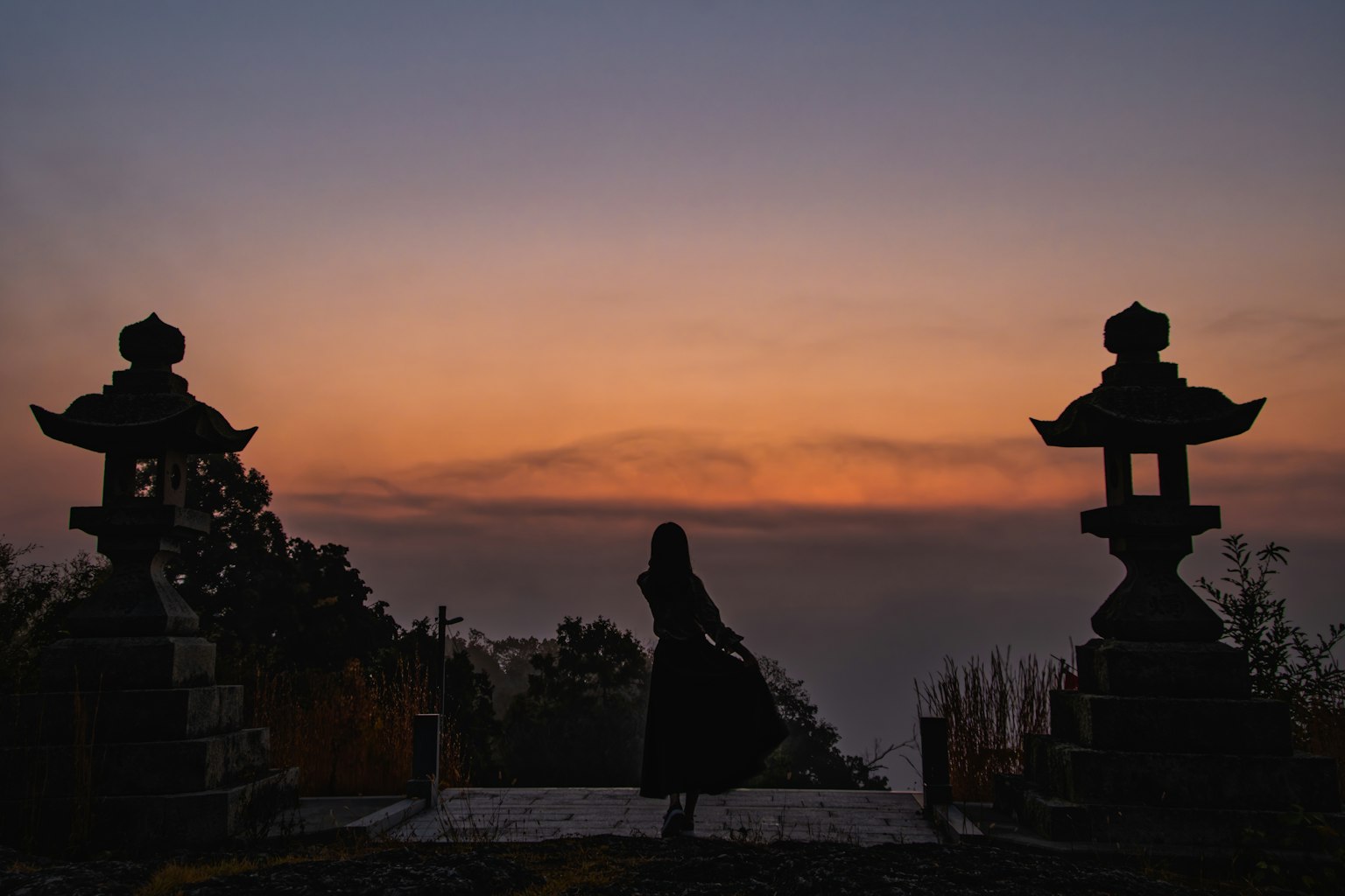 黃昏時分站在寺廟前的女性剪影和石燈籠