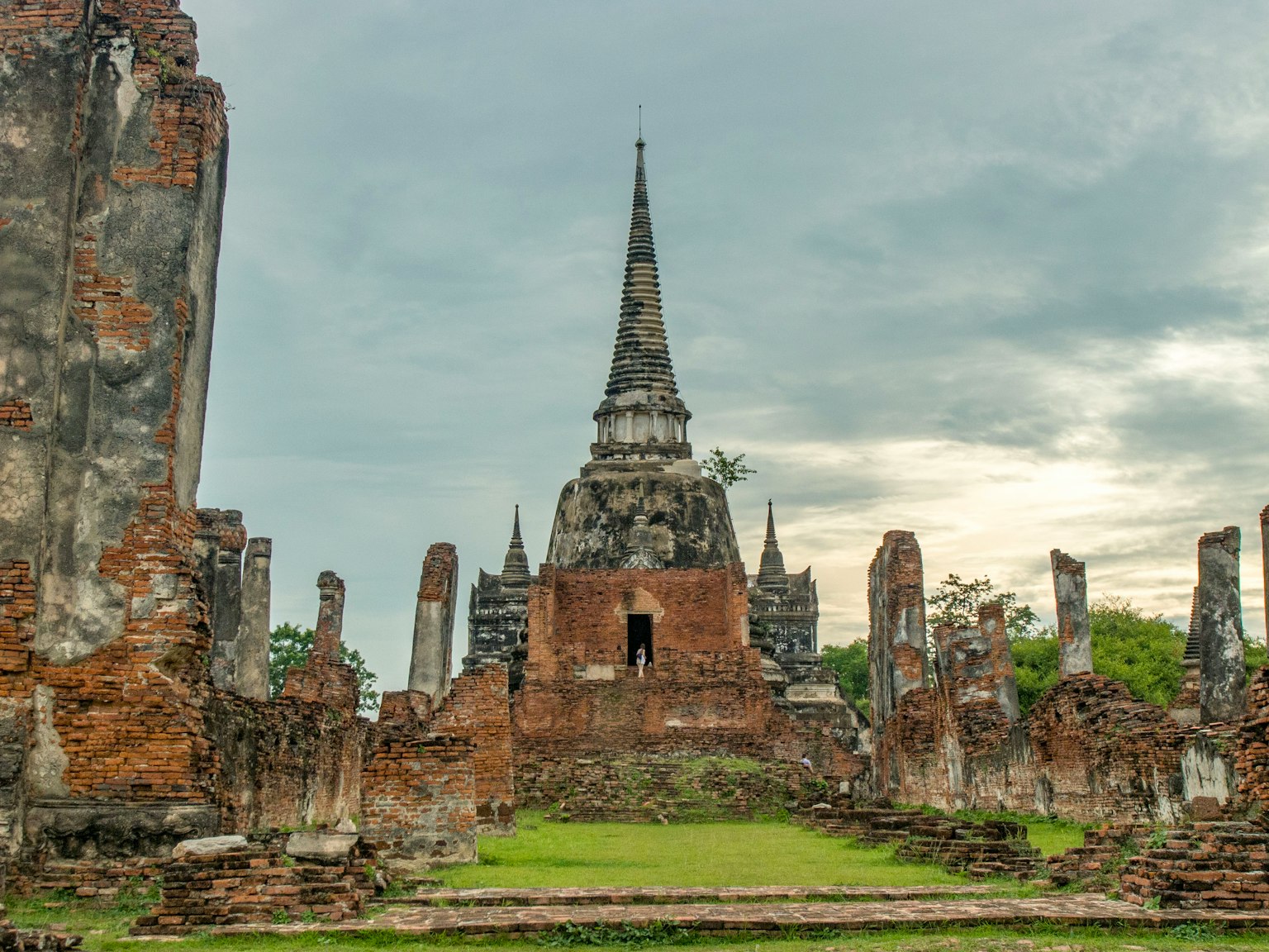Reruntuhan kompleks candi bersejarah Ayutthaya dengan menara tinggi di latar belakang