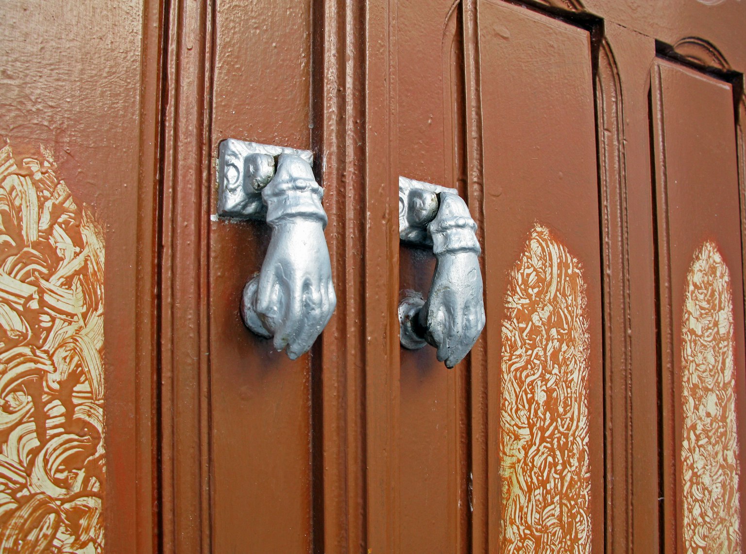 Primer plano de manijas decorativas en una puerta marrón