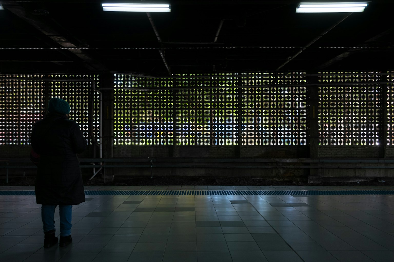 Persona de pie en una plataforma de tren con una pared enrejada