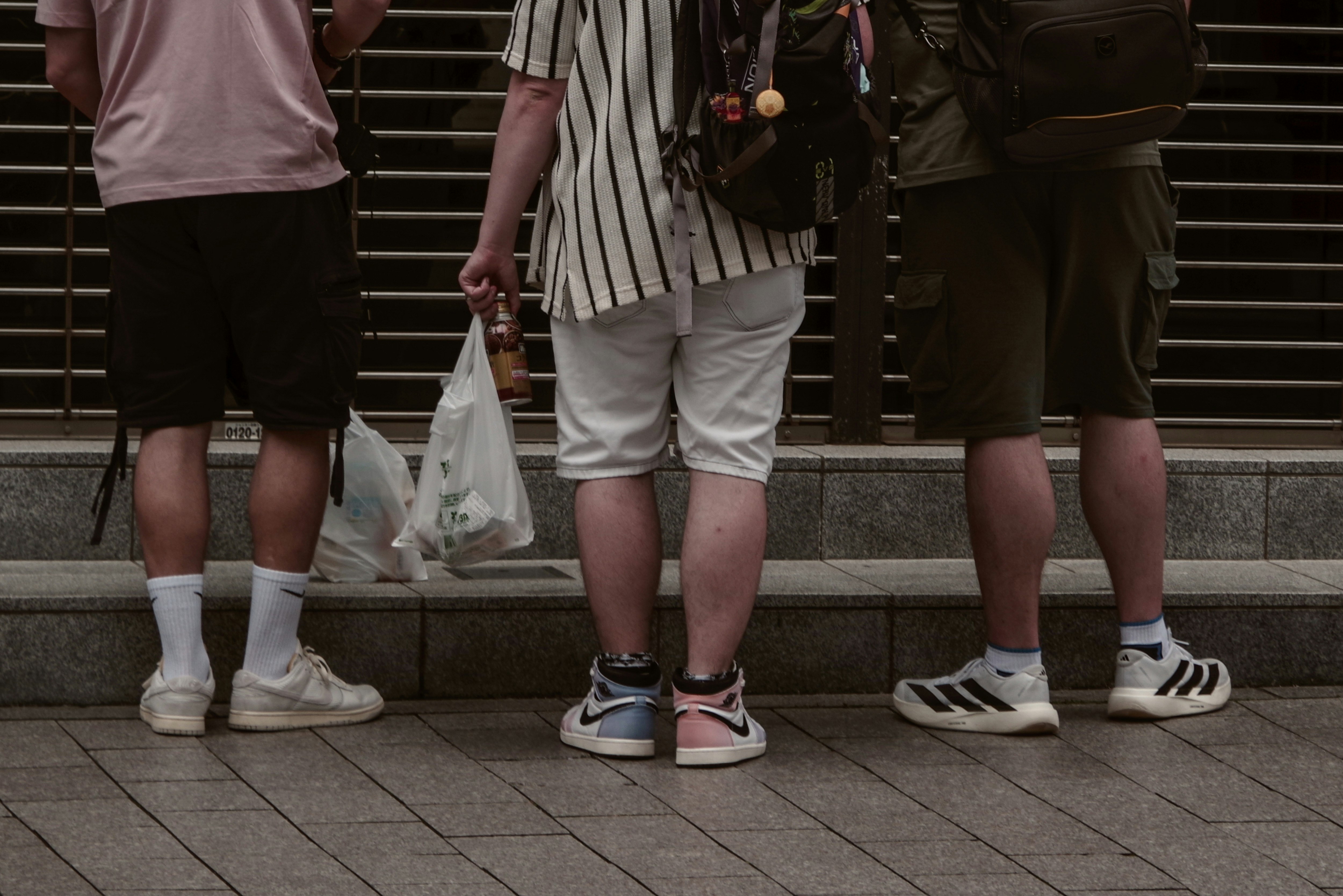 路地のような街角で色違いの靴を並べる人たち