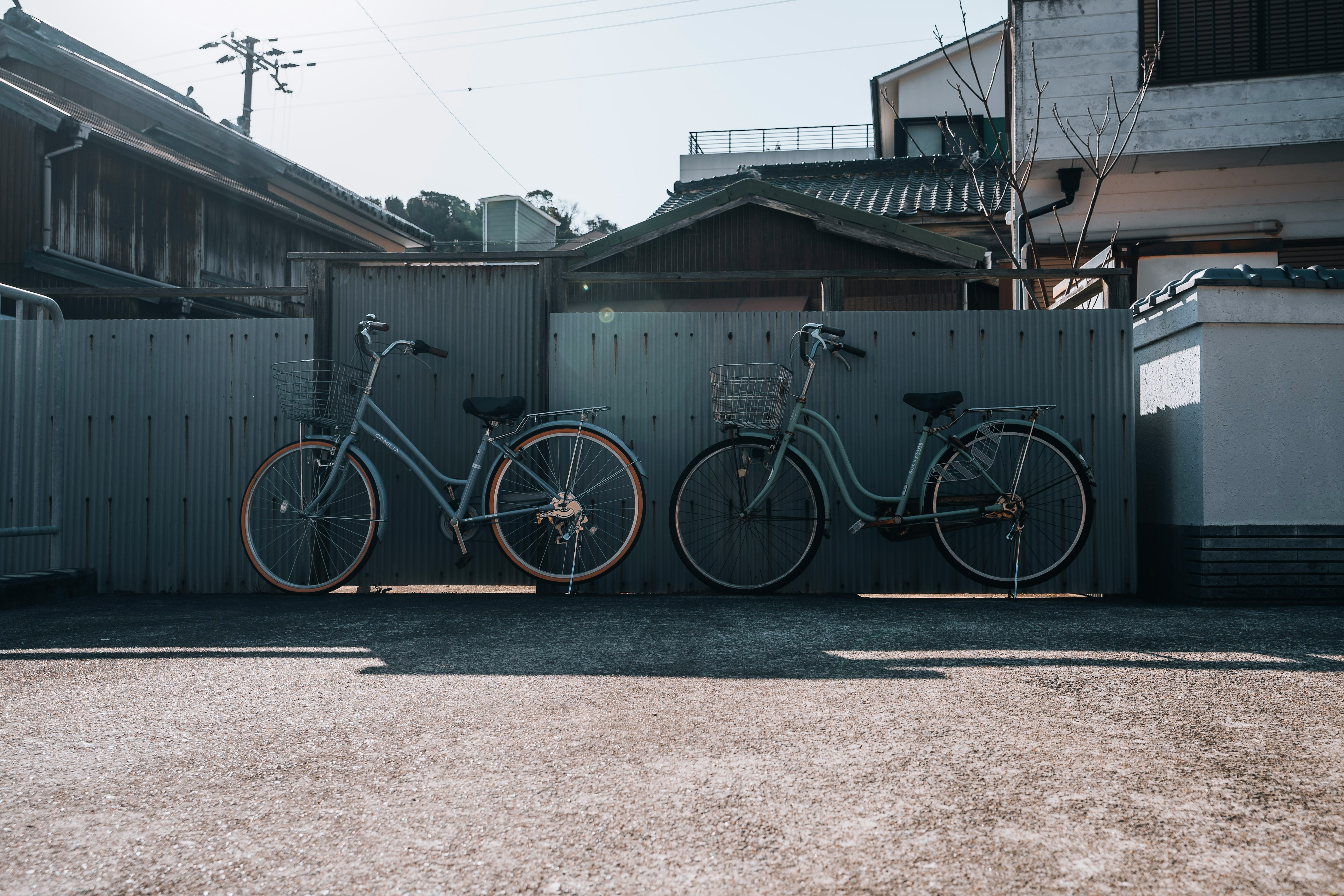 bicycles lined up in front of a fence along a narrow alley