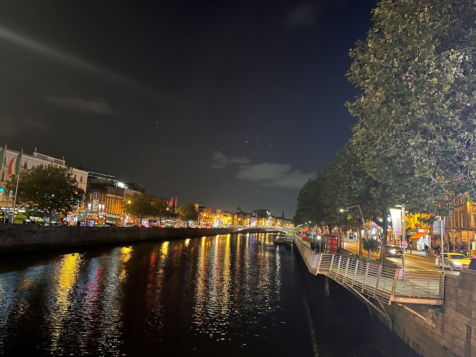 Vista notturna di un paesaggio urbano lungo il fiume con luci che si riflettono sull'acqua
