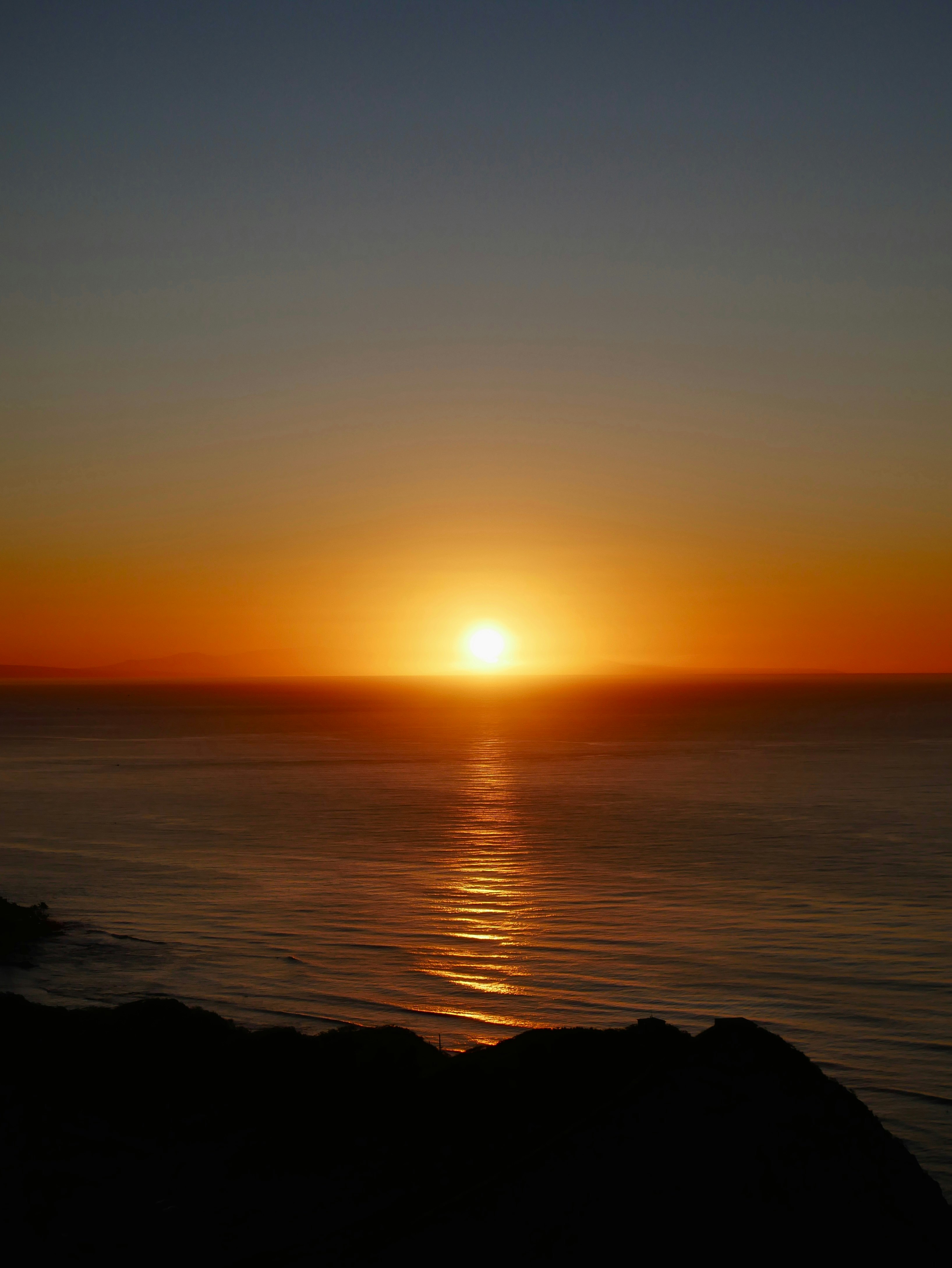 ダイヤモンドヘッドのサミットから見た夕日と海の地平線