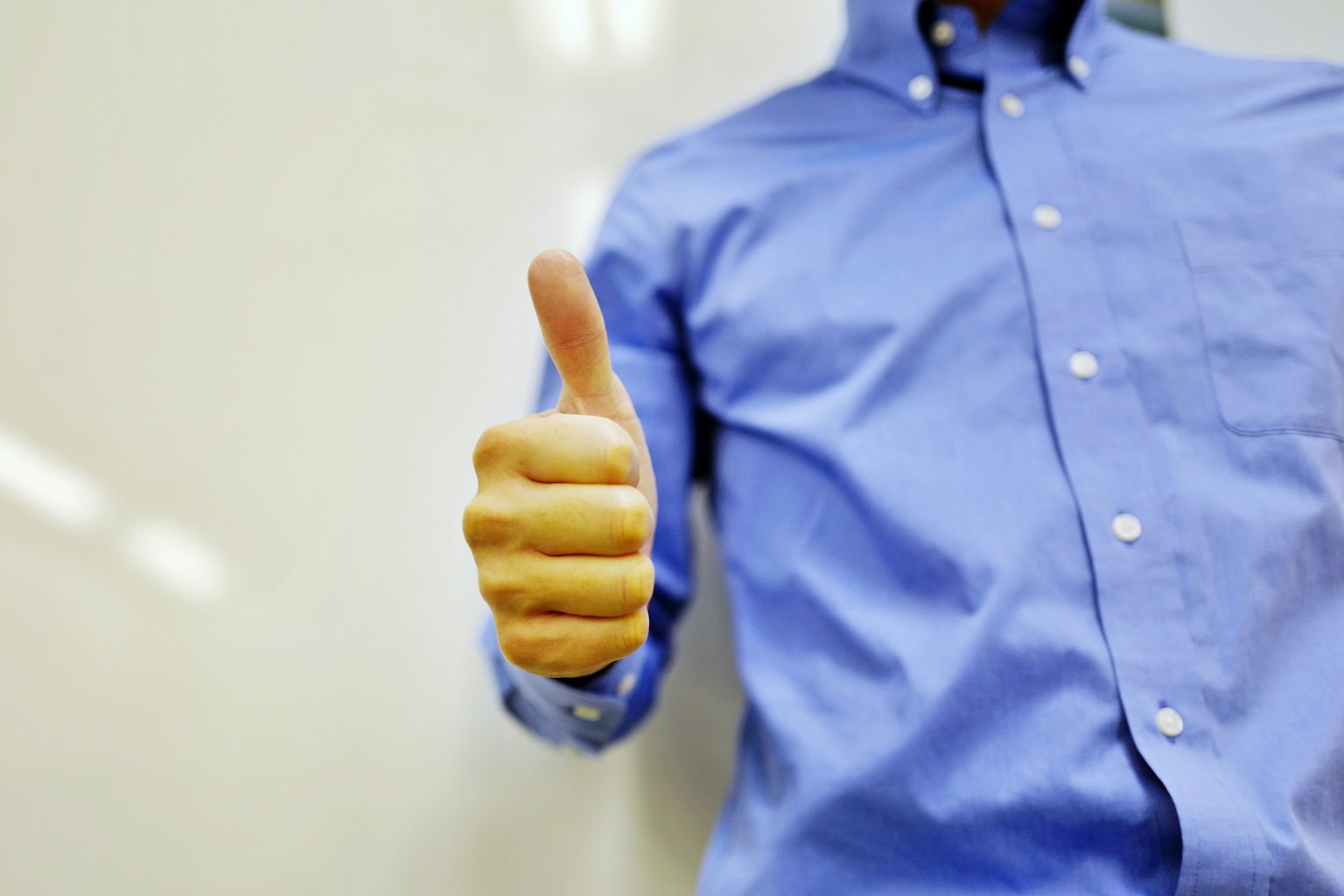 Hombre con camisa azul haciendo un pulgar hacia arriba