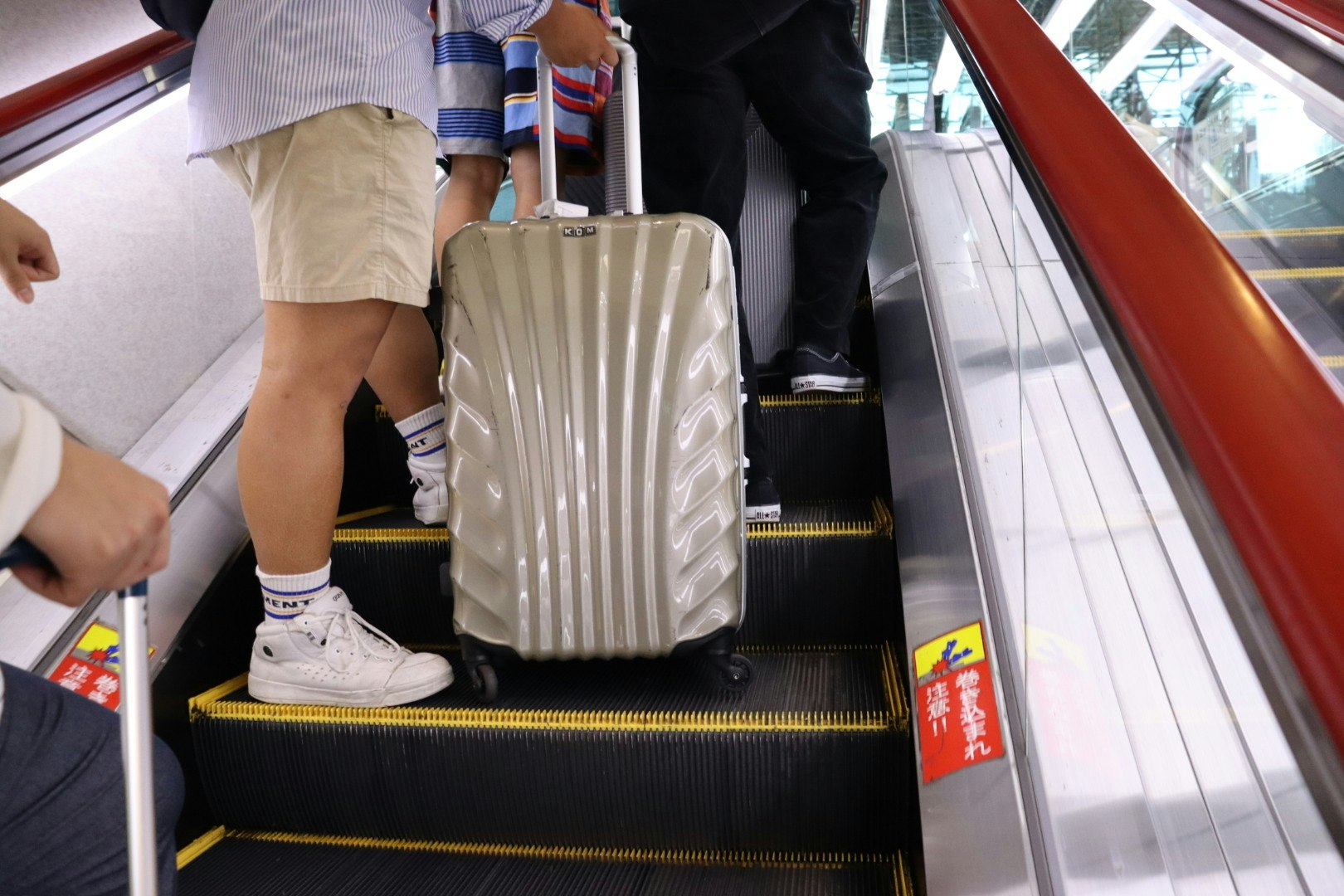 空港のエスカレーターでキャリーケースを持つ旅行者の足元
