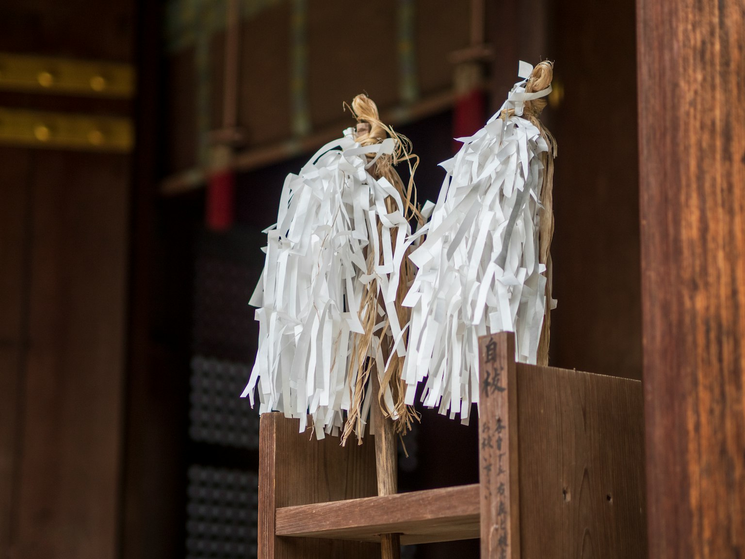 Decoraciones blancas de shimenawa en un soporte de madera en un santuario