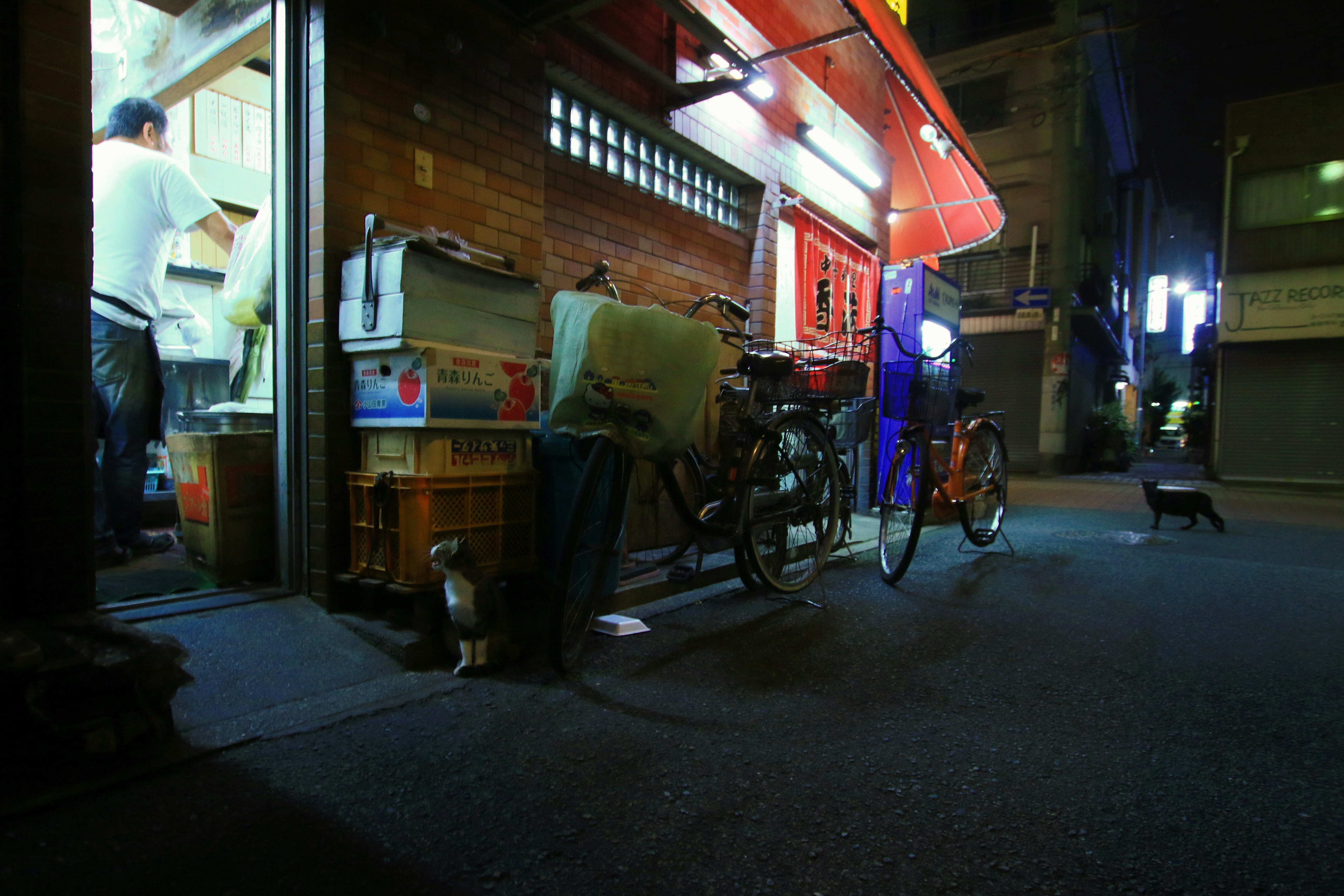 路地の町中華店先に並ぶ自転車と看板のある夜の街並み