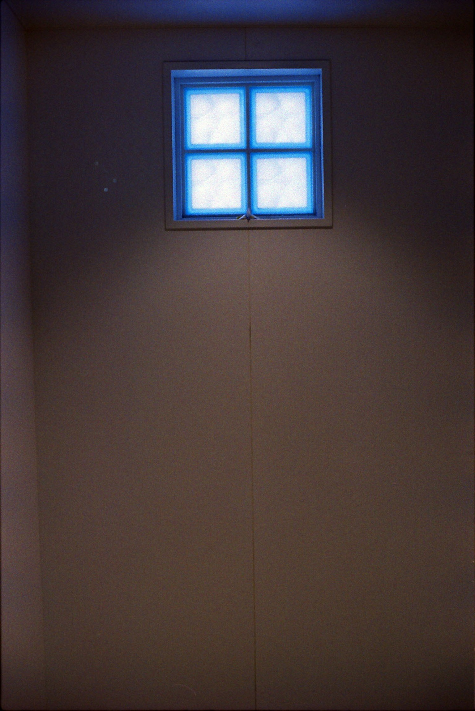 Interno con un muro scuro e una finestra illuminata di blu