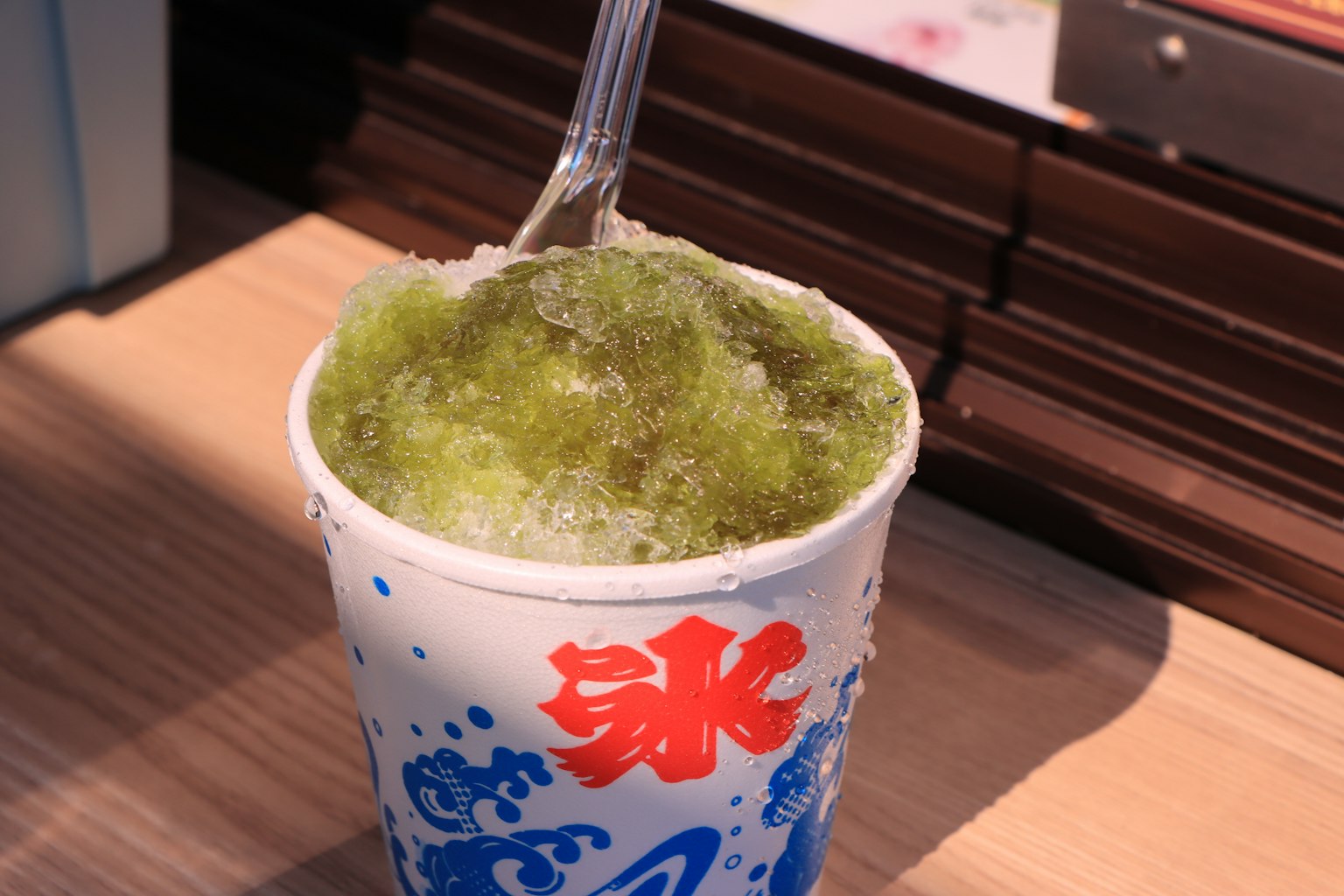 Cup of matcha shaved ice topped with green syrup