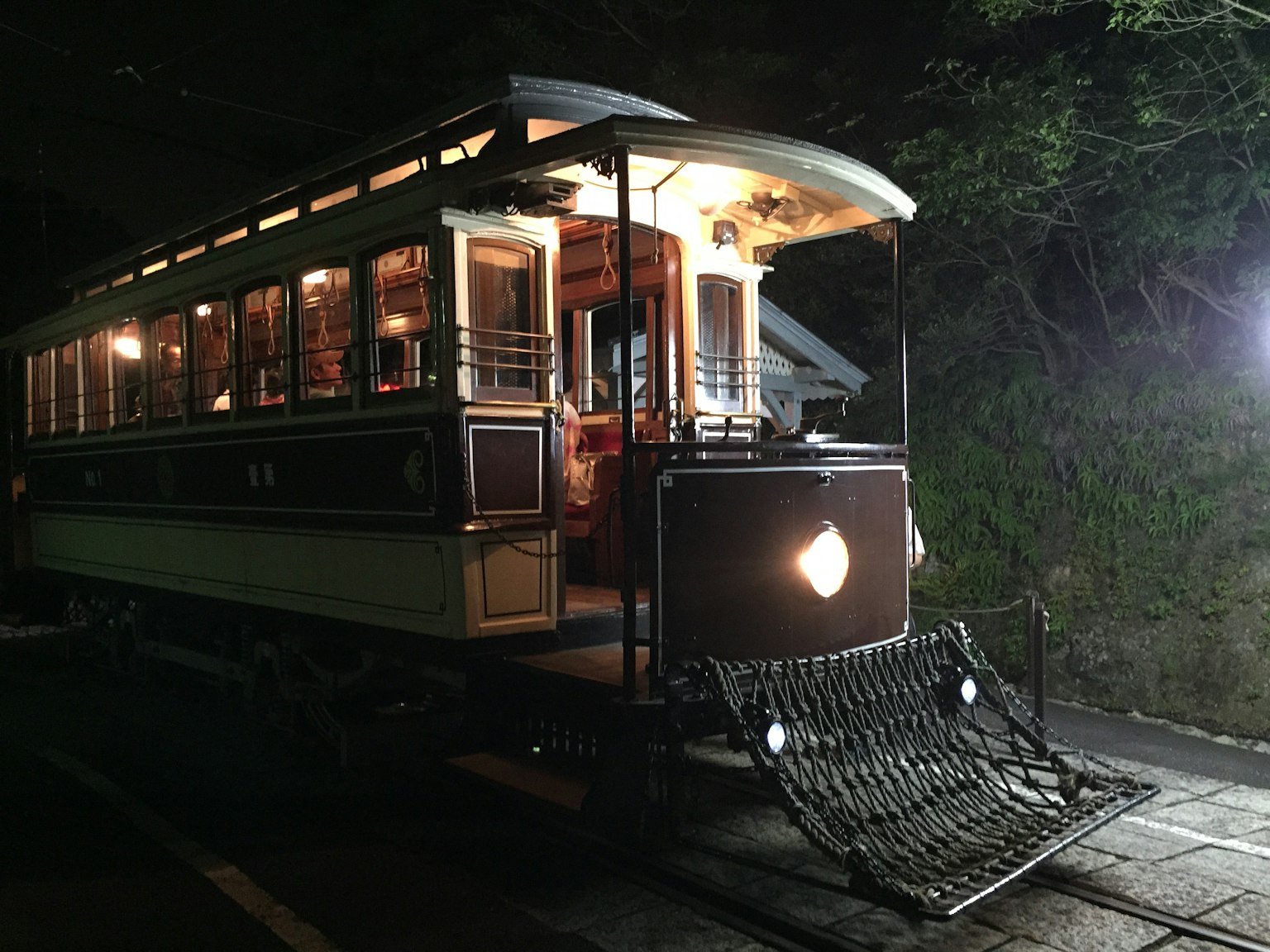 Un tranvía vintage iluminado por la noche con exterior de madera y ventanas brillantes