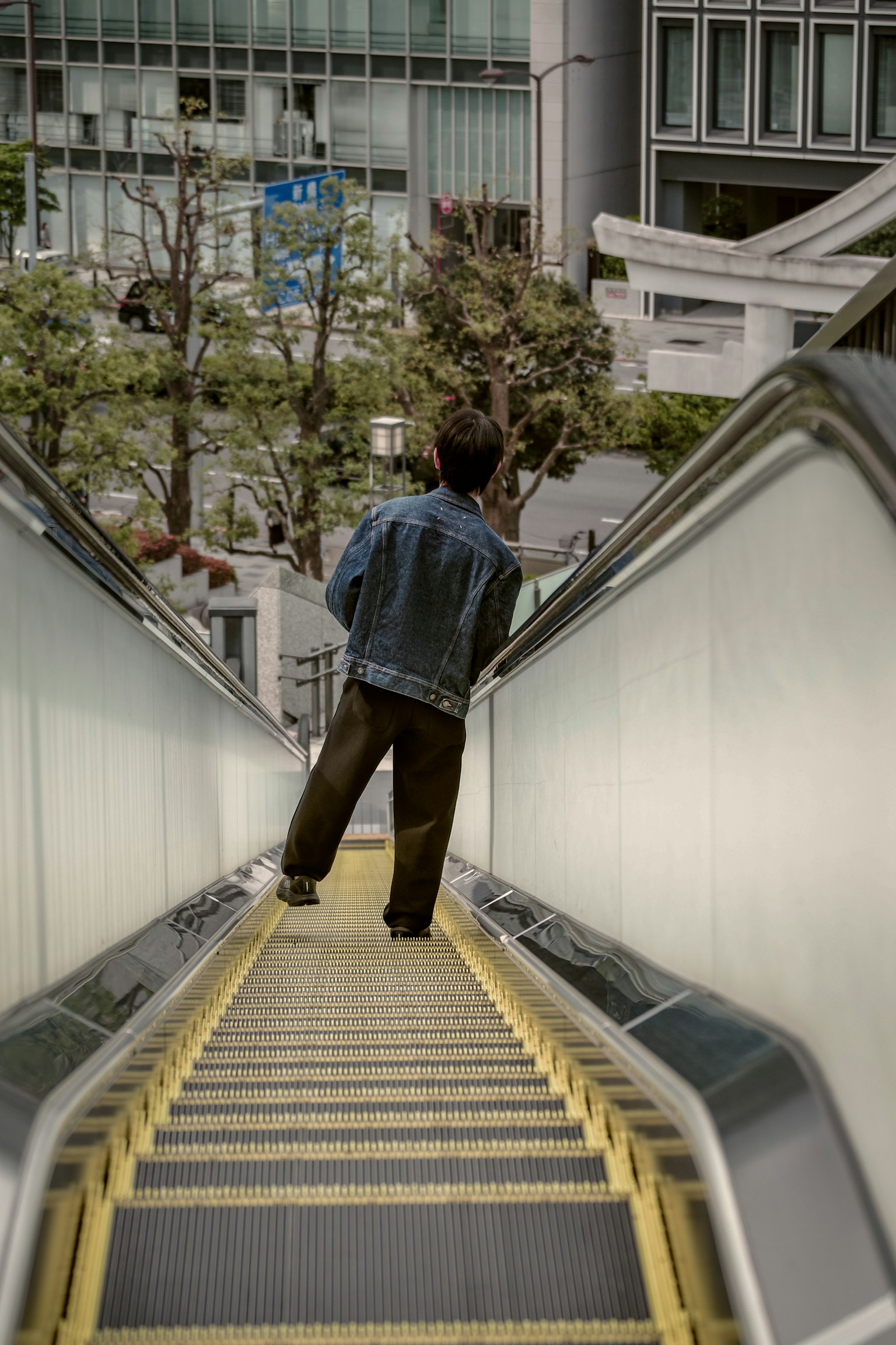 Orang berdiri di eskalator dengan pemandangan kota di latar belakang