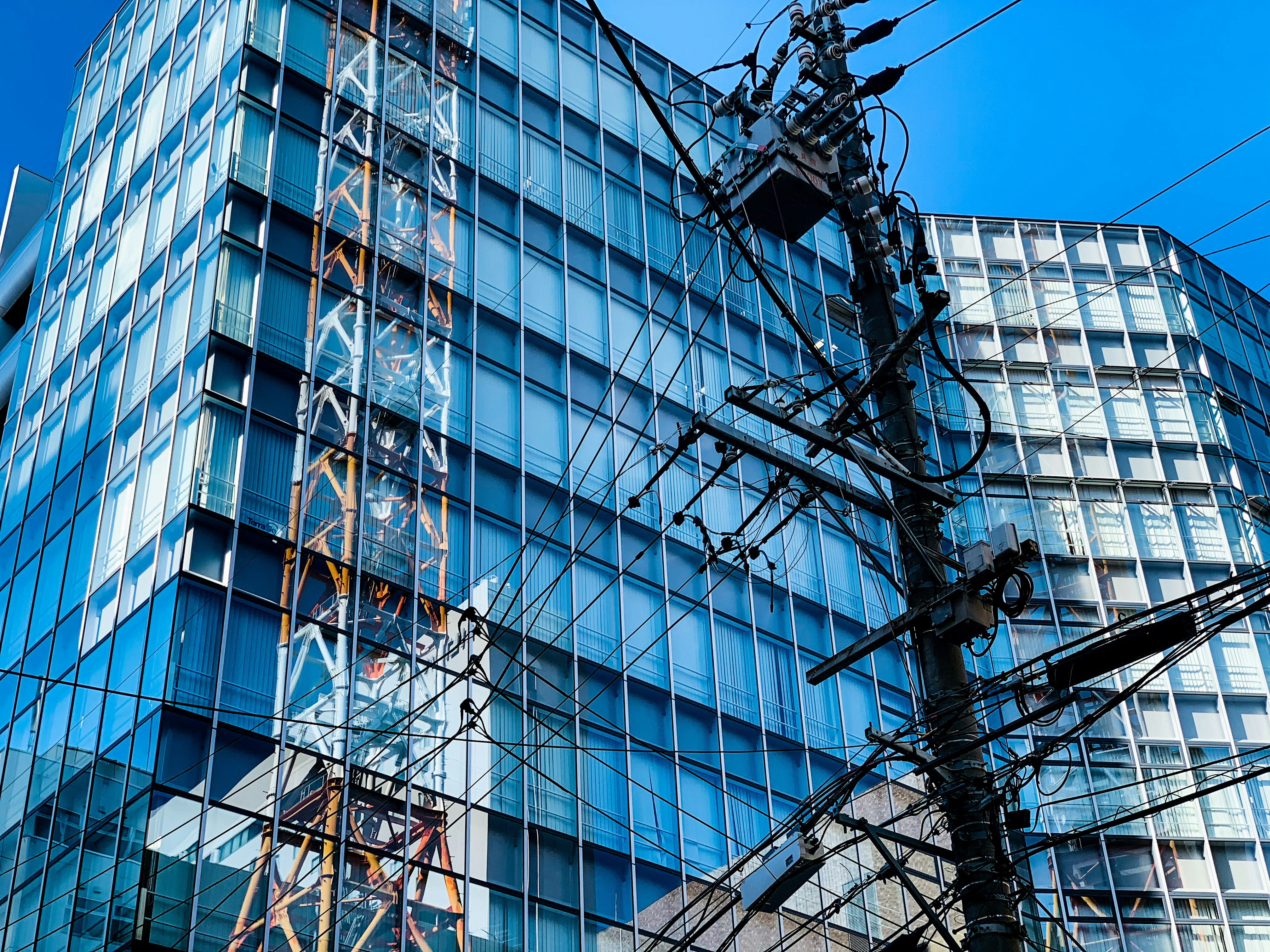 edificio per uffici in vetro blu con cavi aerei in un contesto urbano