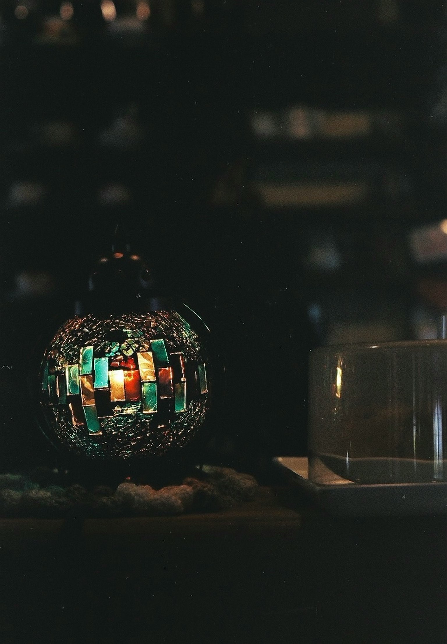 Decorative object emitting colorful light against a dark background with a clear glass container
