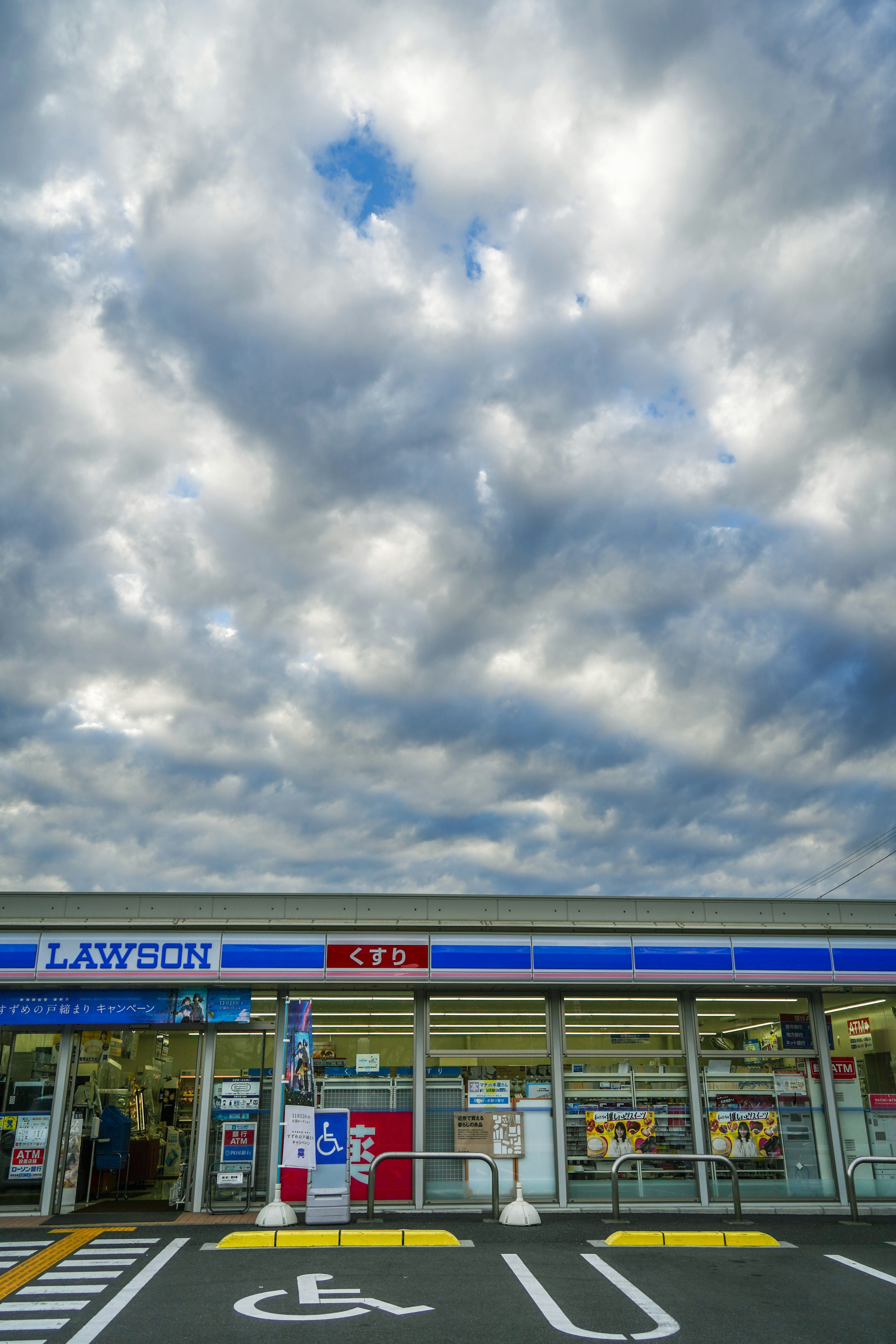 Eingang eines Lawson-Geschäfts mit Parkmarkierungen unter blauem Himmel