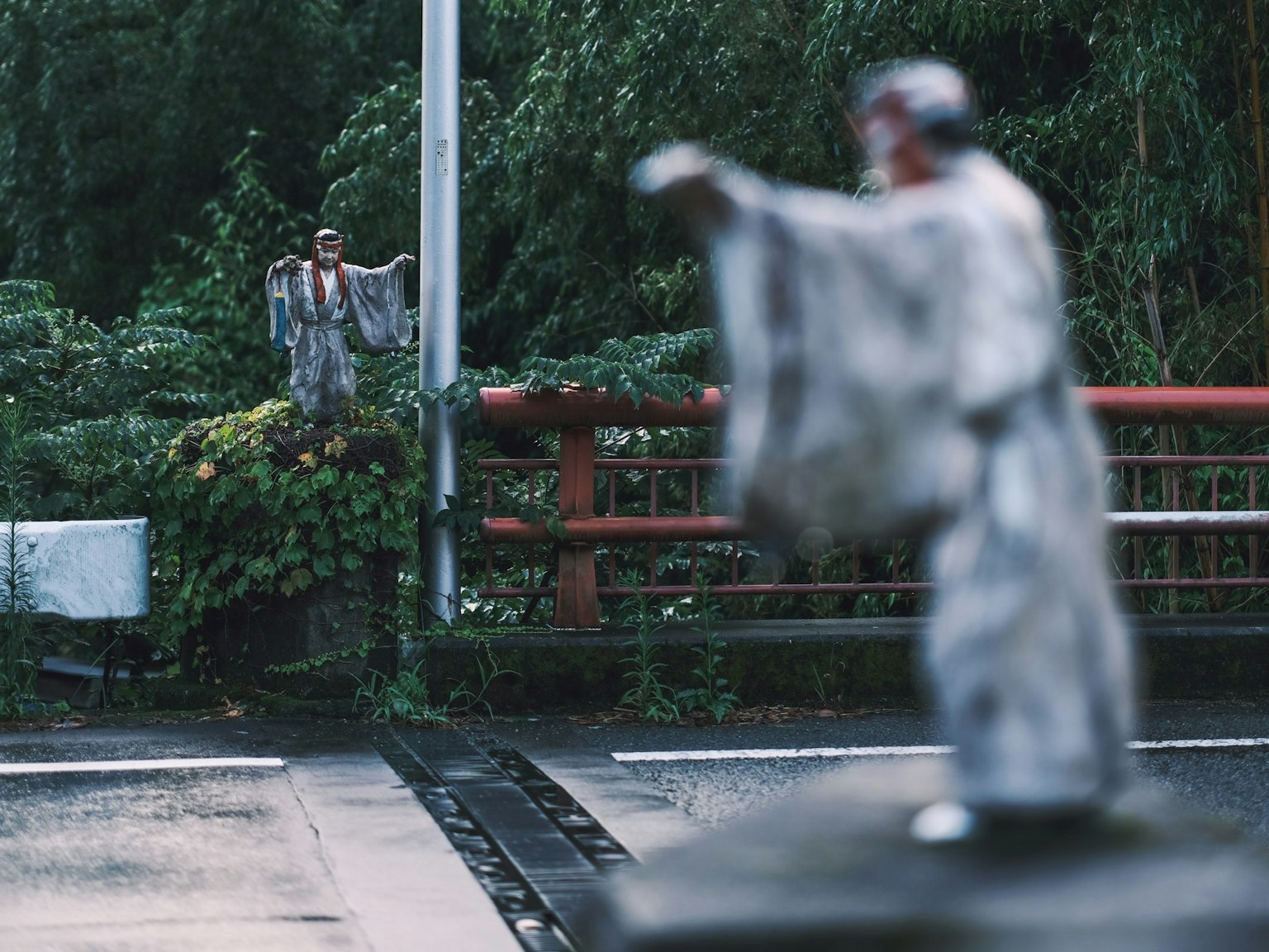 Deux statues dans la brume avec un pont rouge en arrière-plan