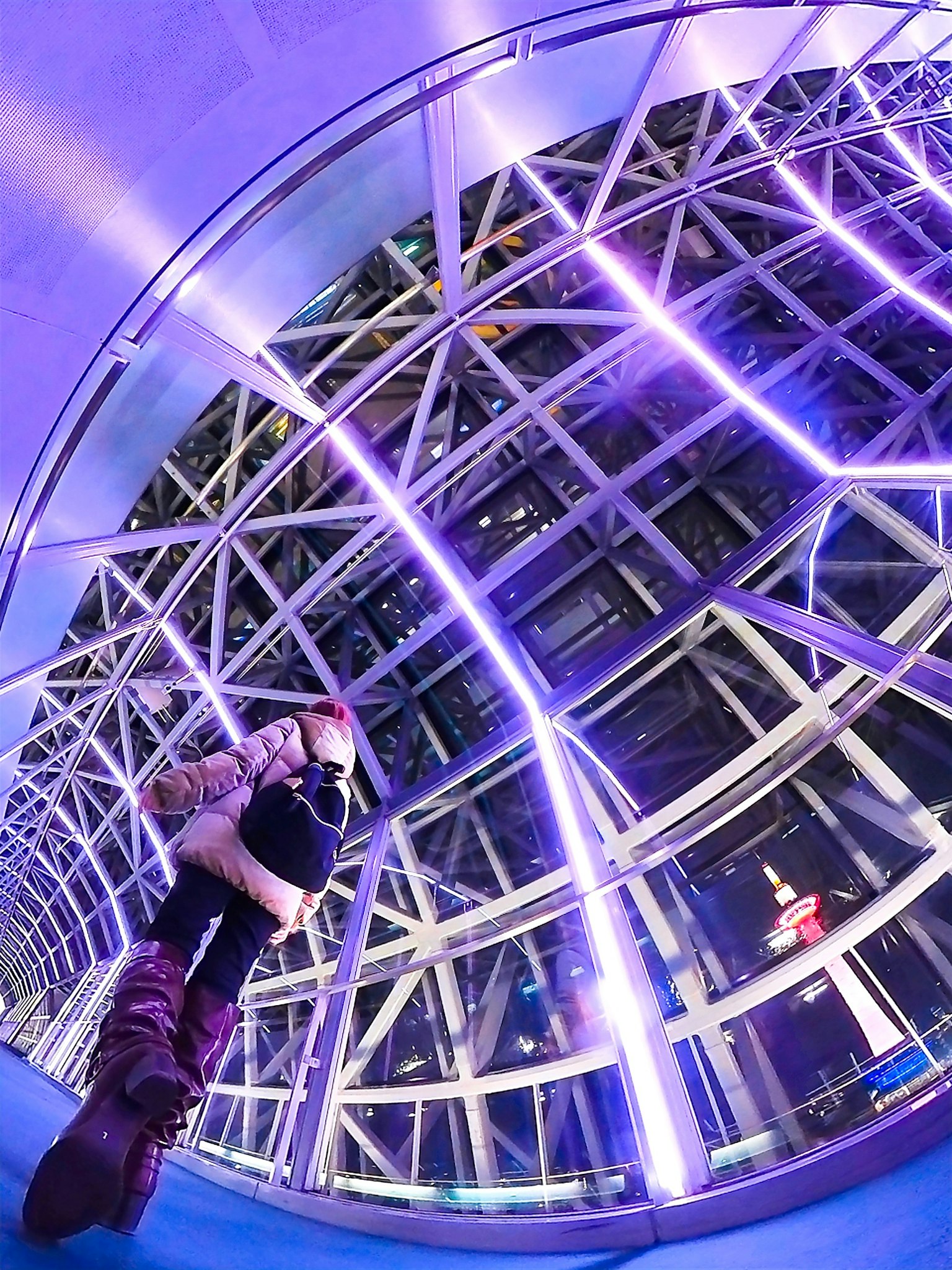 Person walking through a modern architectural structure illuminated by purple lights