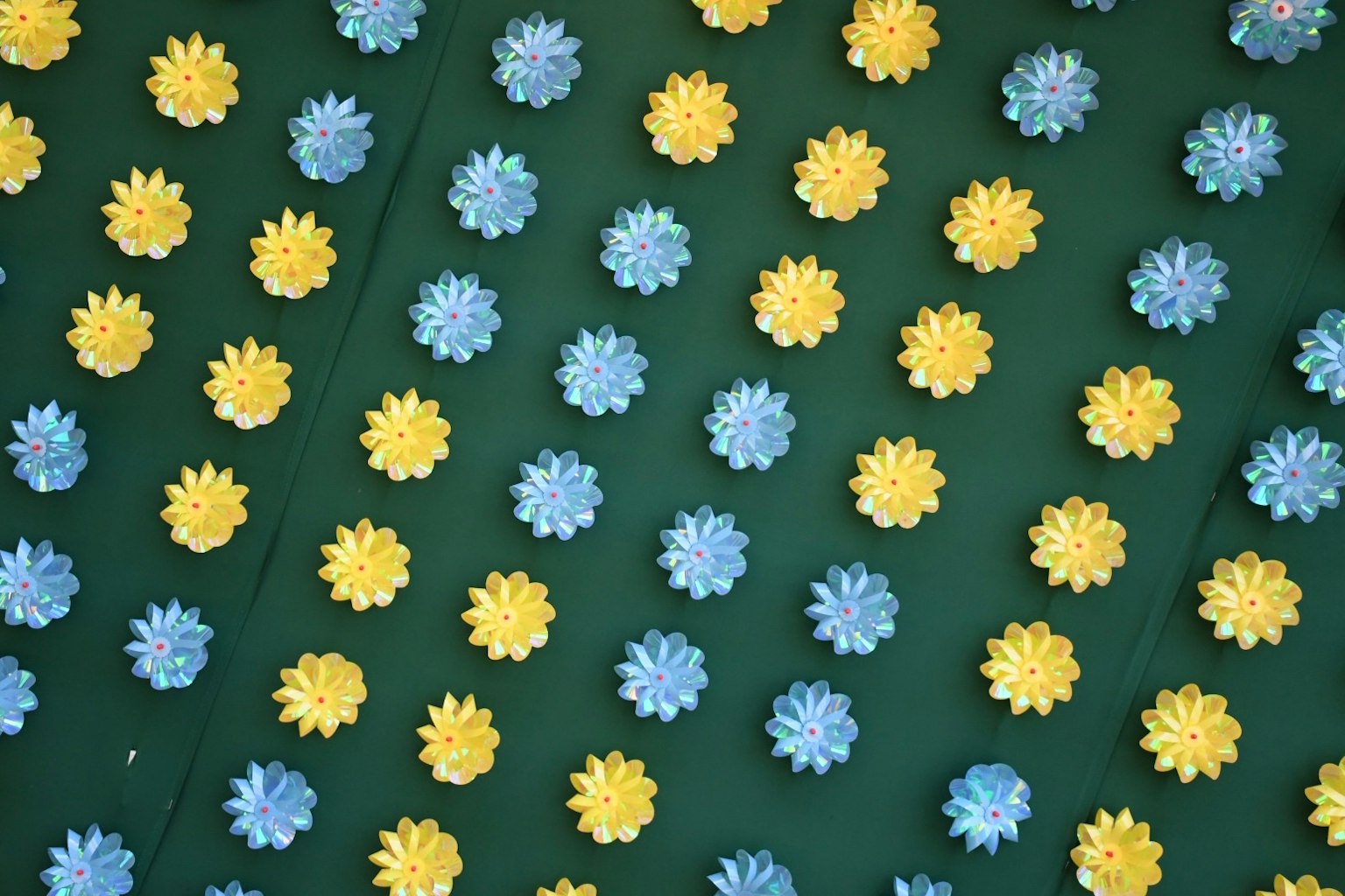 Muster von blauen und gelben Blumen auf grünem Hintergrund verstreut