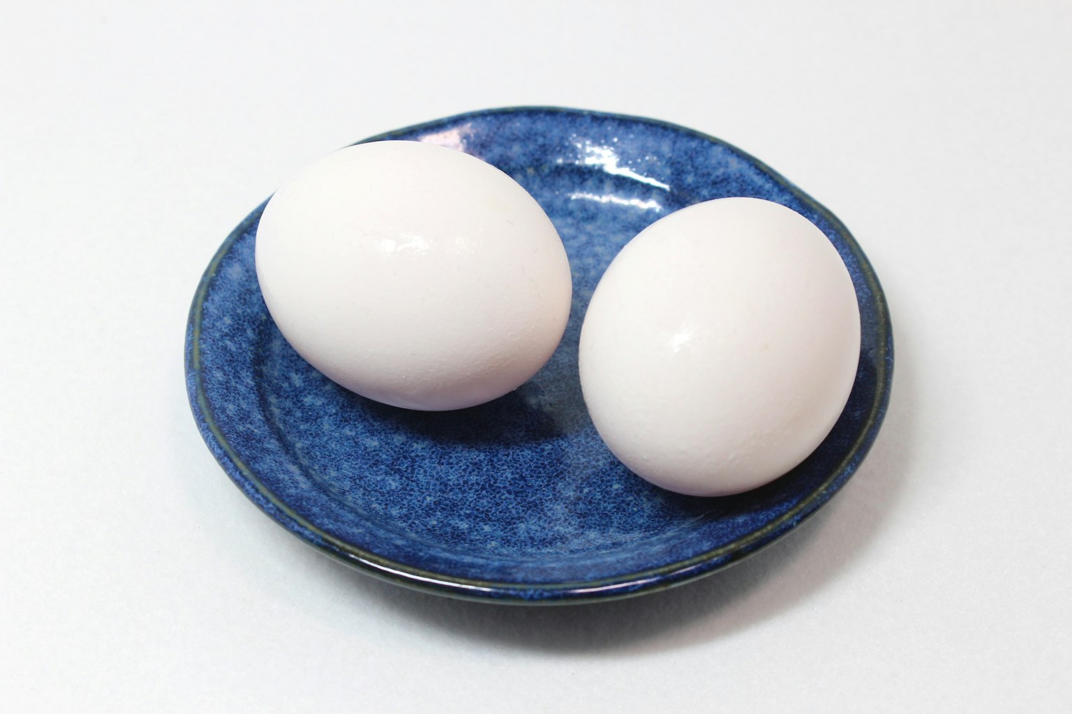 Deux œufs blancs sur une assiette bleue