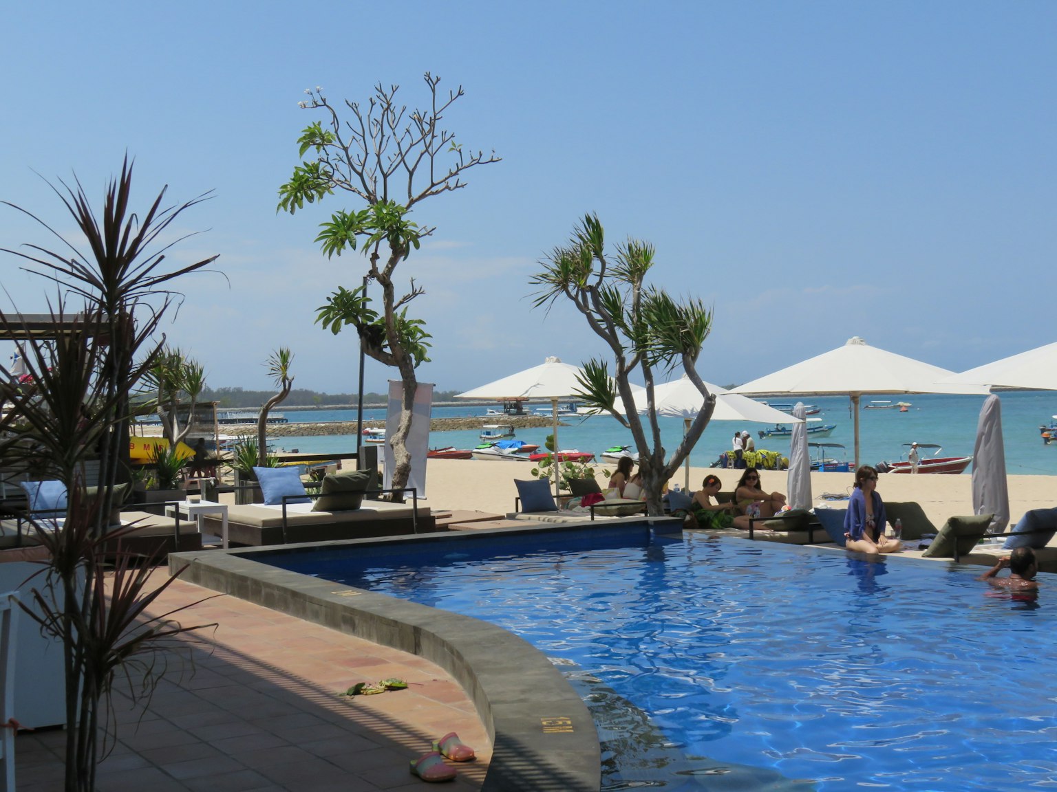 Beach resort view with blue pool and white umbrellas