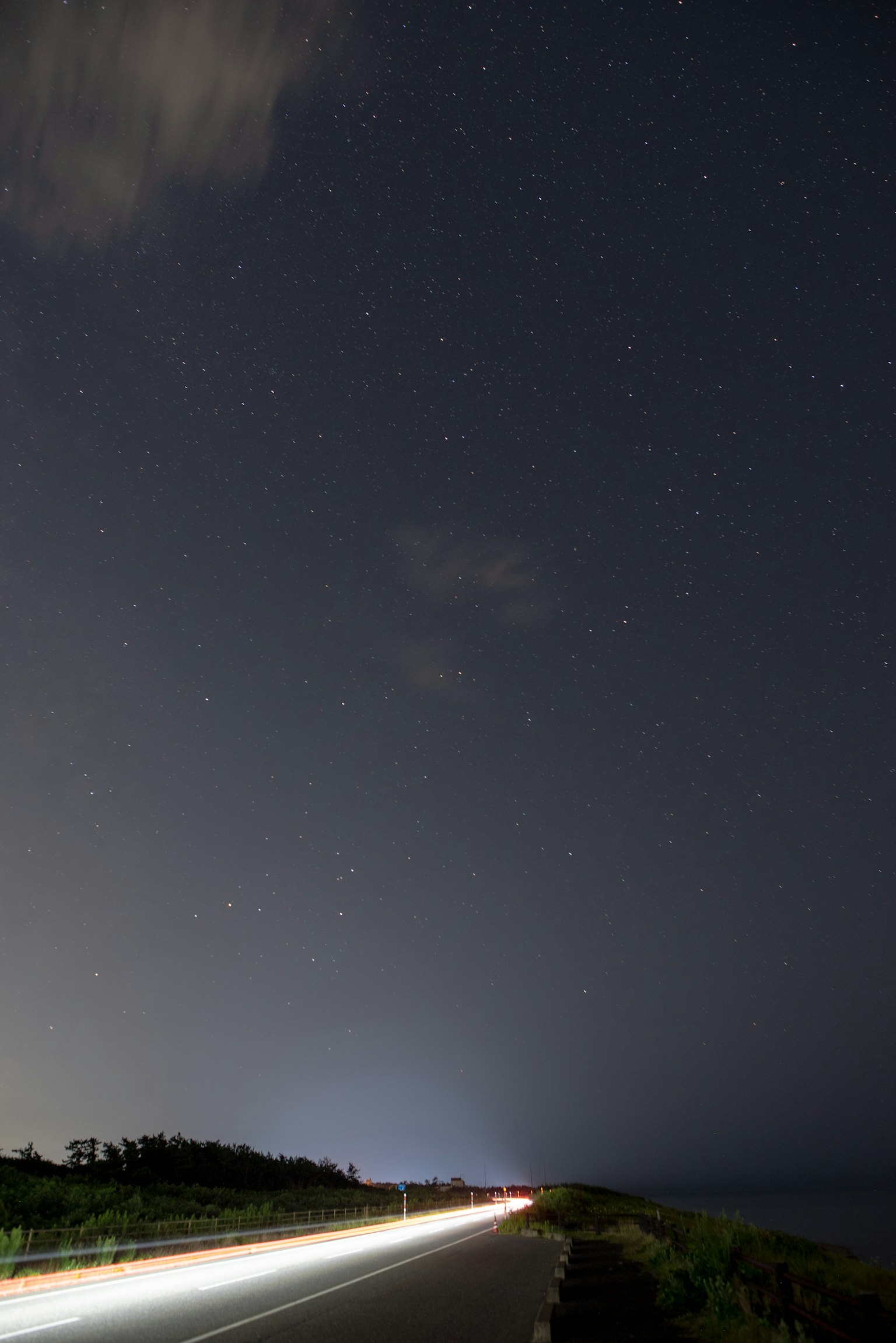 Route sous un ciel étoilé avec des traînées lumineuses de véhicules