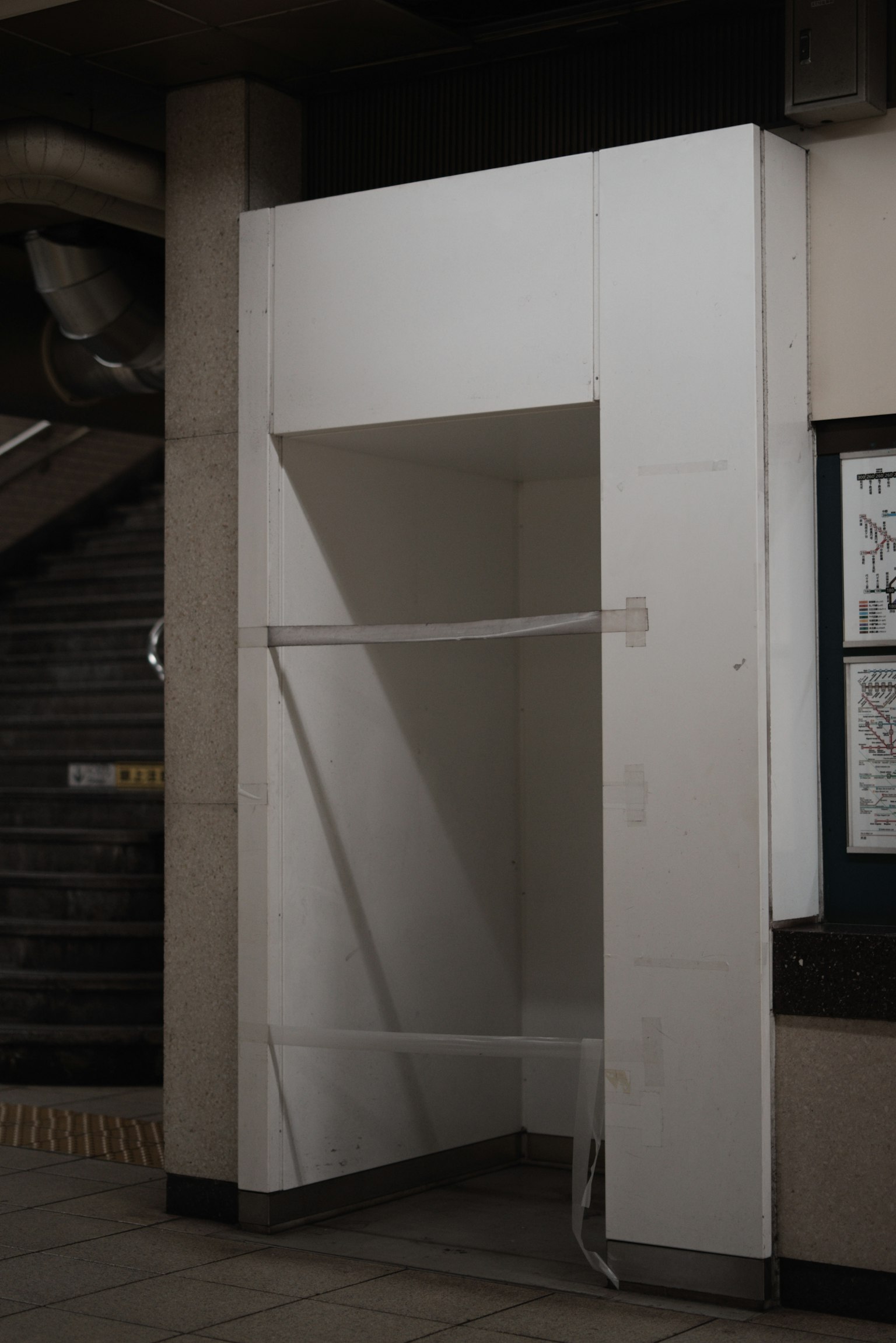 Eine kleine Öffnung in einer weißen Wand mit einem transparenten Seil in einer U-Bahn-Station