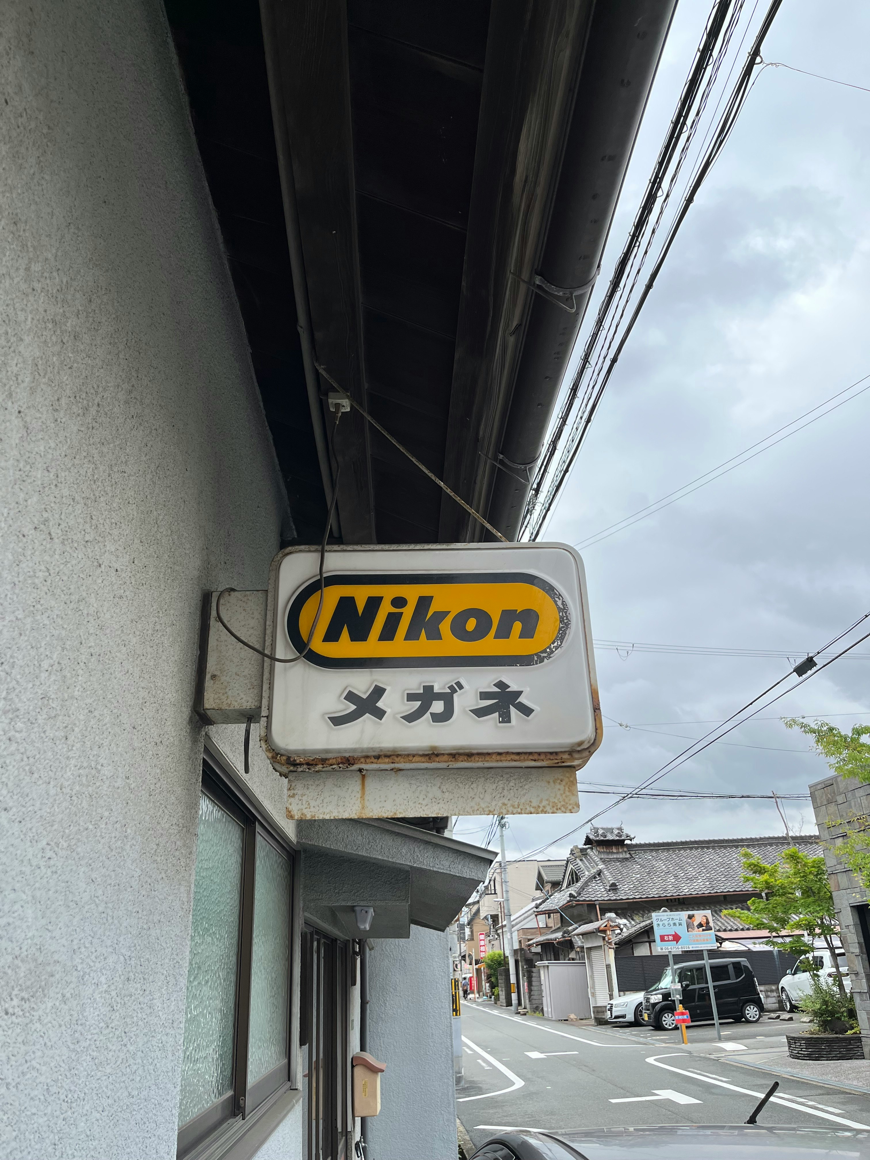 軒先に掲げられたNikonの看板とメガネ店のある路地の街並み
