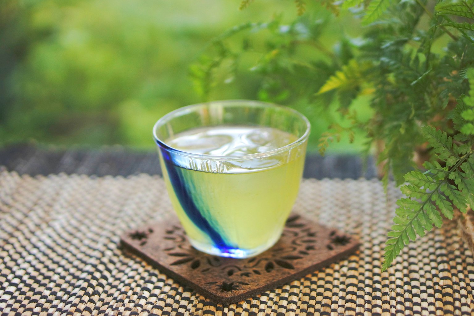 Transparent drink in a blue-striped glass with a green background