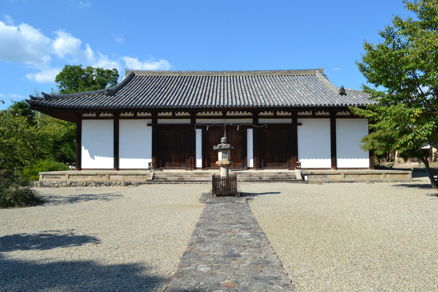 Edificio japonés tradicional con paredes blancas y techo de tejas camino de piedra y linterna en el jardín