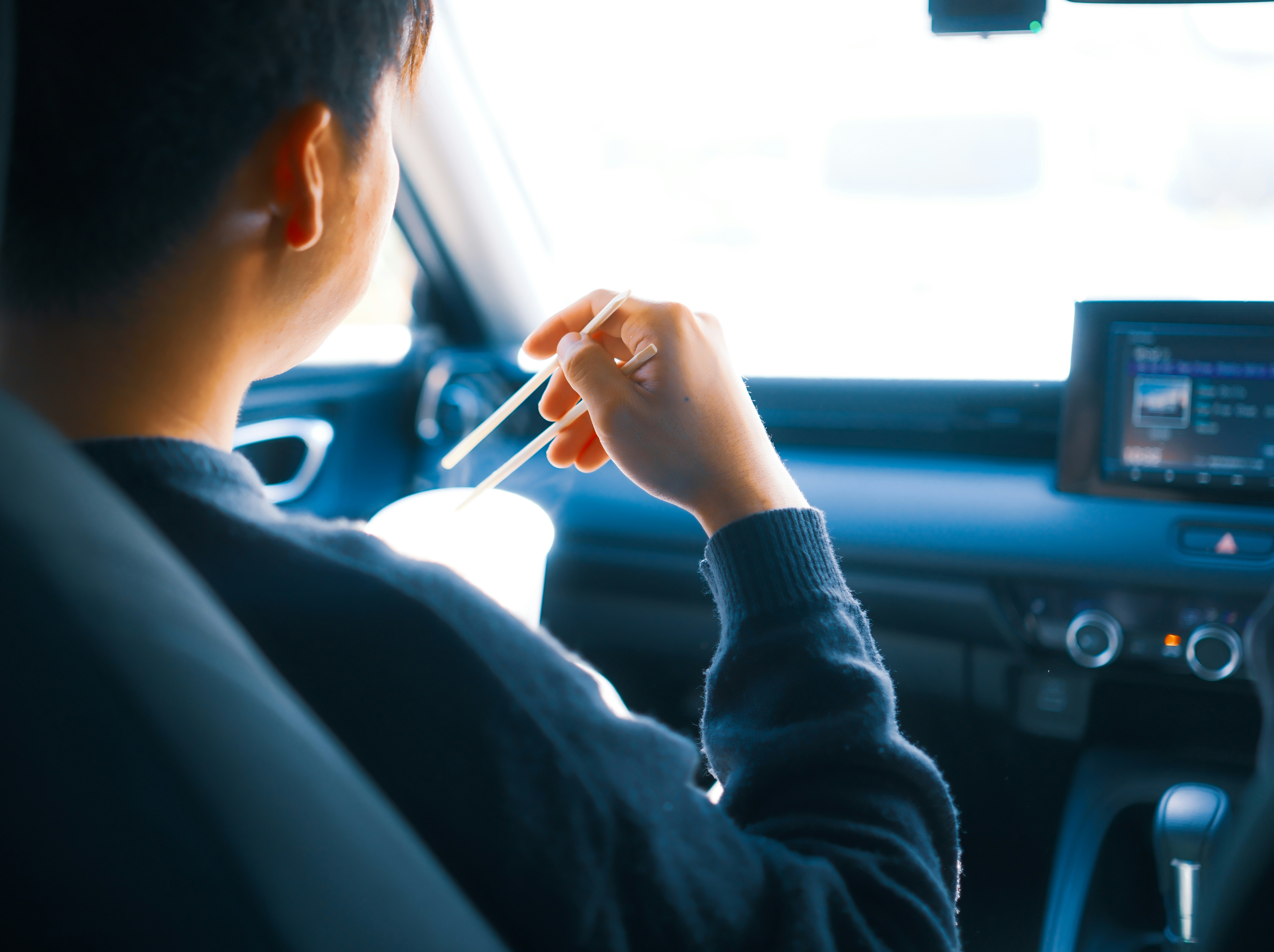 車内で箸を持って食べる人の横顔