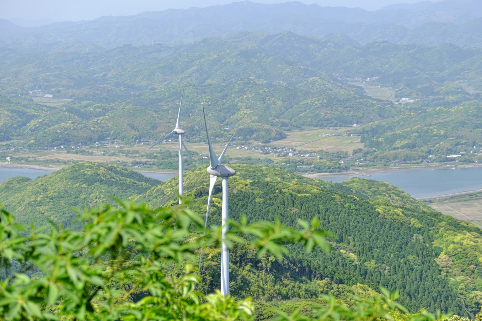 Pemandangan turbin angin di antara pegunungan hijau dan sungai