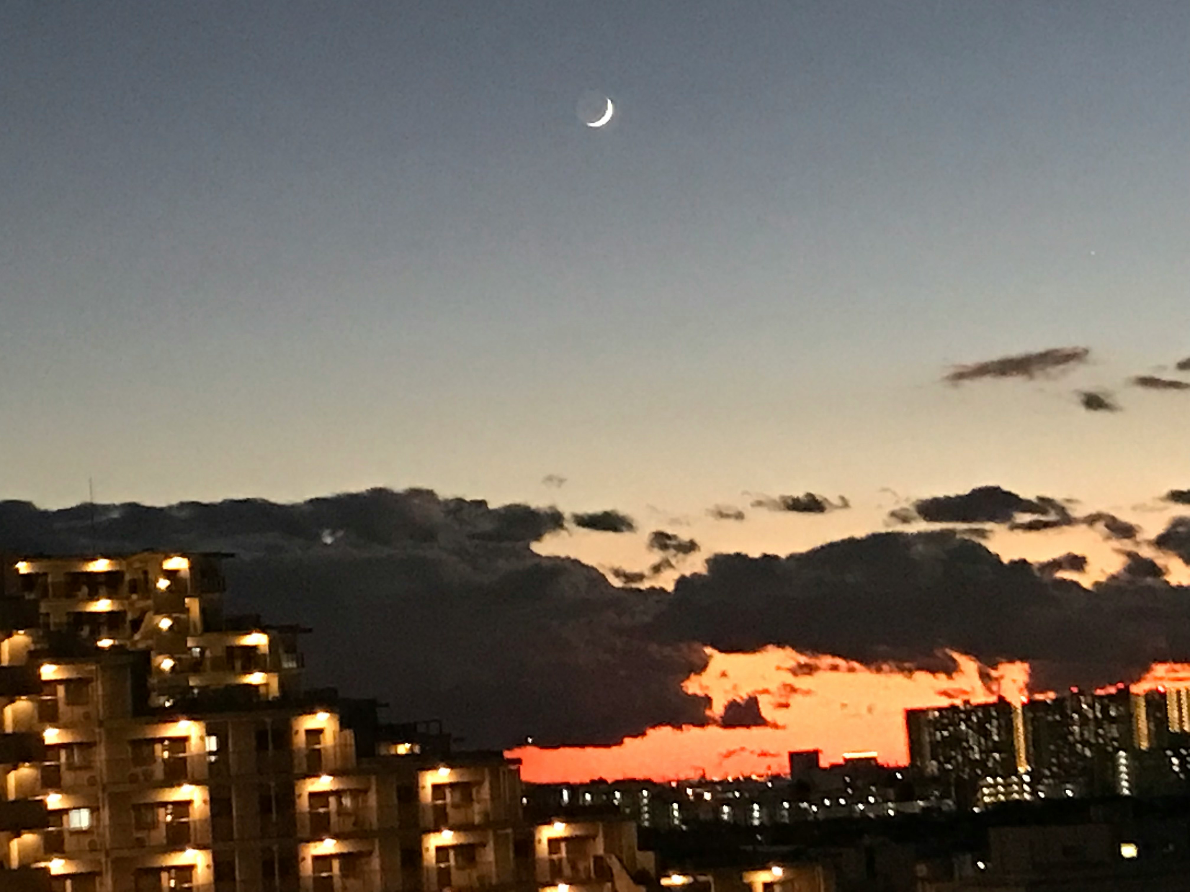 丘の上の住宅街と夕焼けの空に浮かぶ月