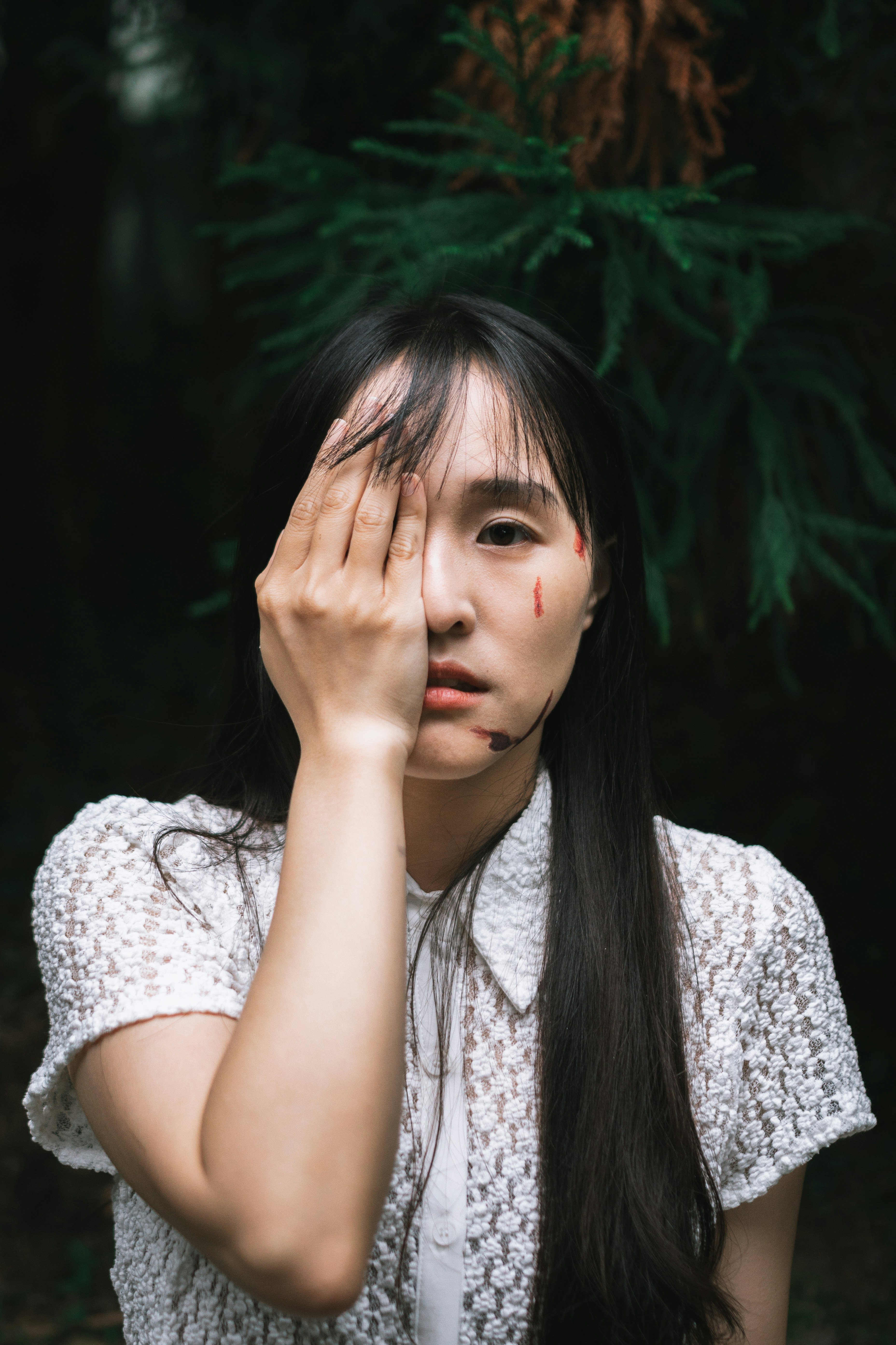 手で頬を隠しながら見つめる女性のポートレート
