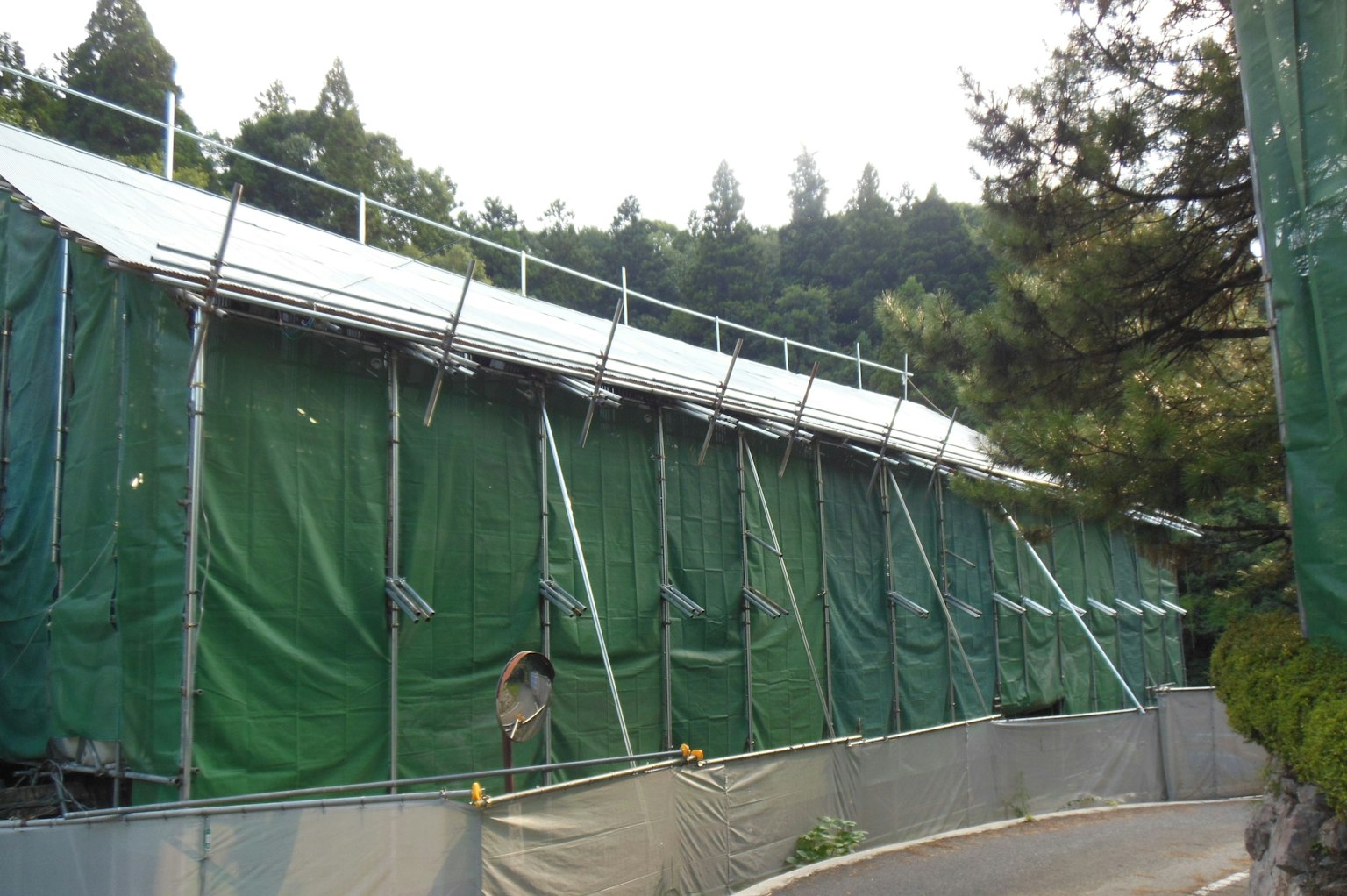 Vue extérieure d'un bâtiment recouvert de bâches vertes avec échafaudage
