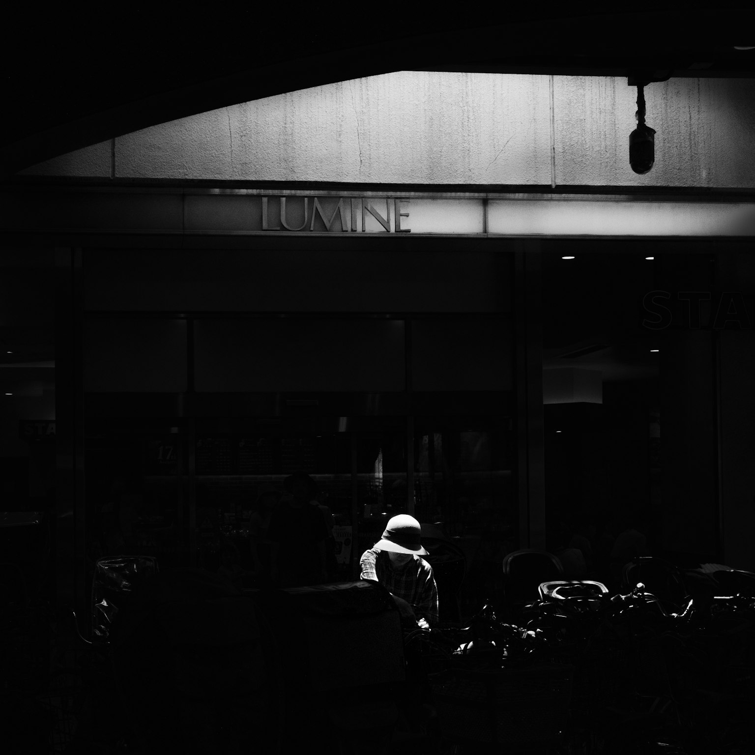 一個街景，背景昏暗，穿著白色連帽衣服的人物